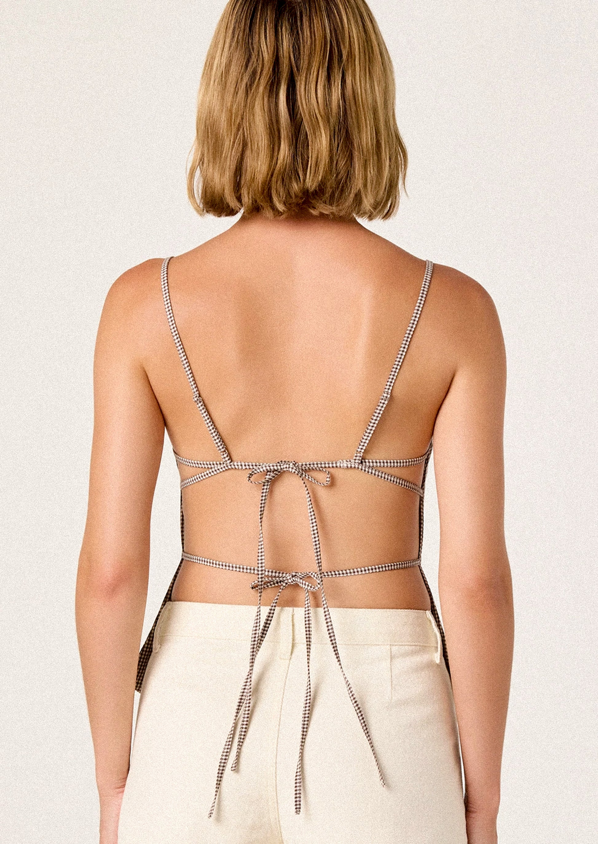 Woman wearing a strappy top with a plain background