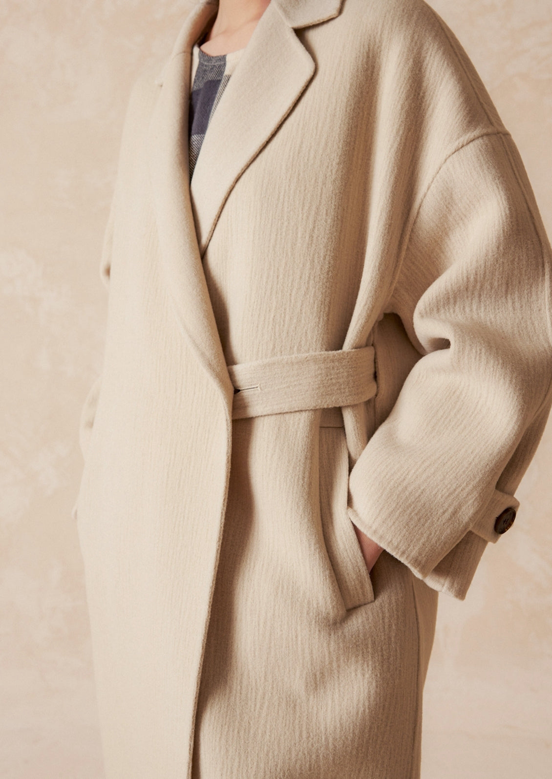 A woman wearing a wool coat with subtle texture and tab closure.