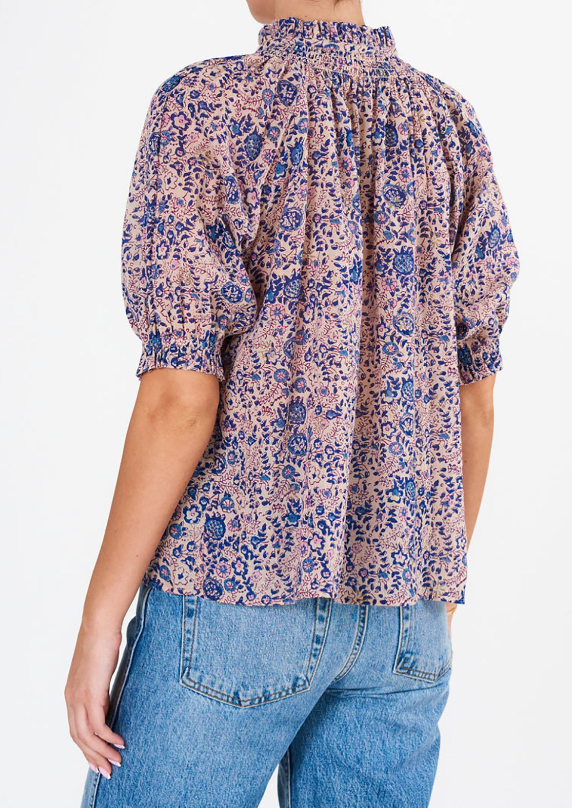 A woman wearing a floral block printed shirt with short sleeves.