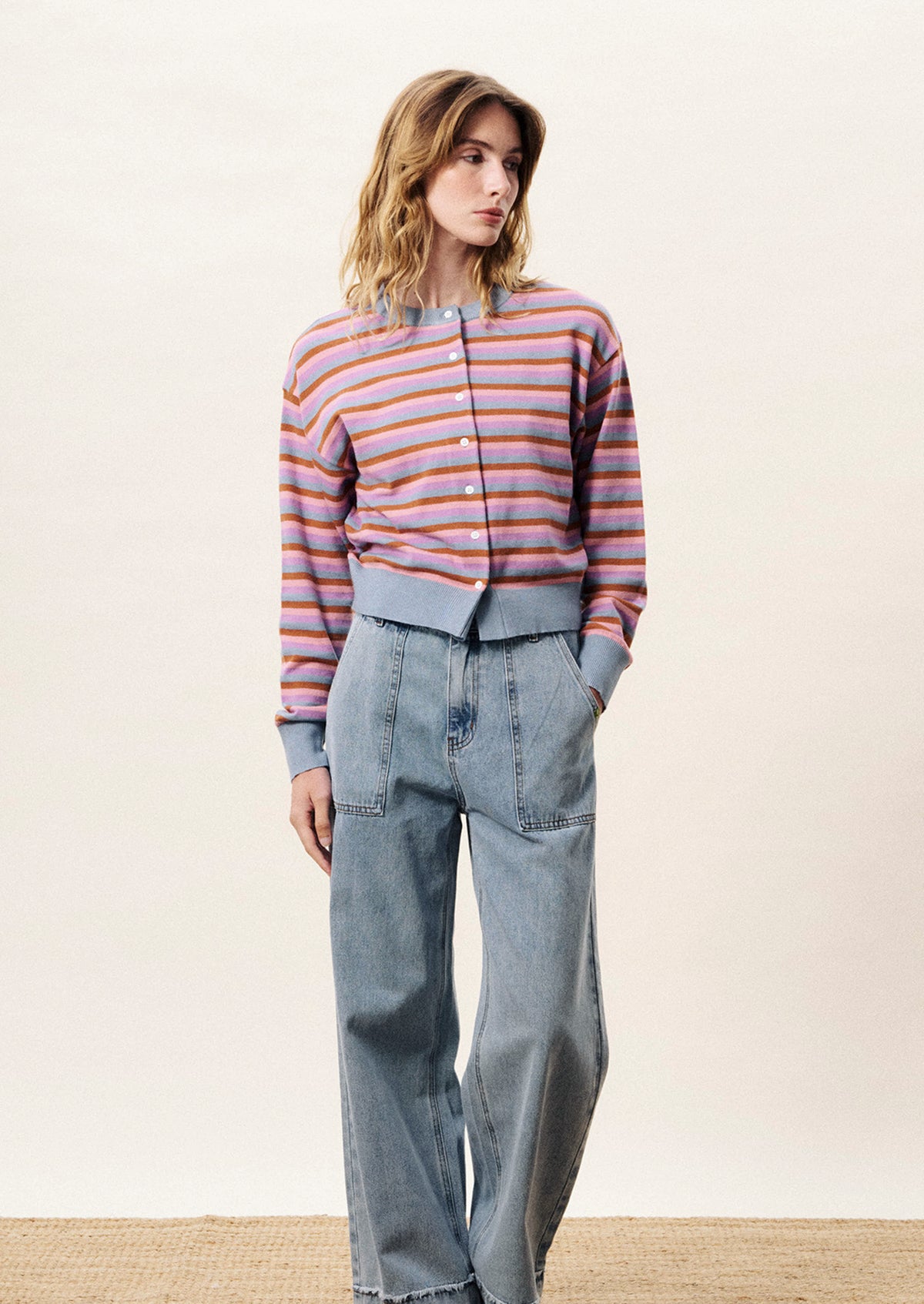 Woman wearing a striped sweater and jeans on a plain background