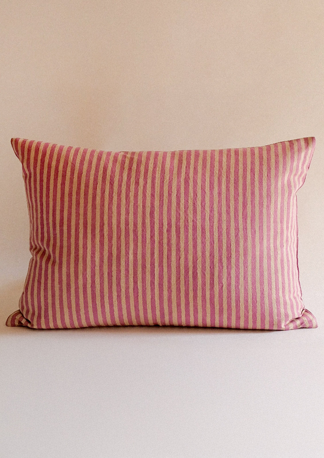 A beige and pink striped lumbar throw pillow.