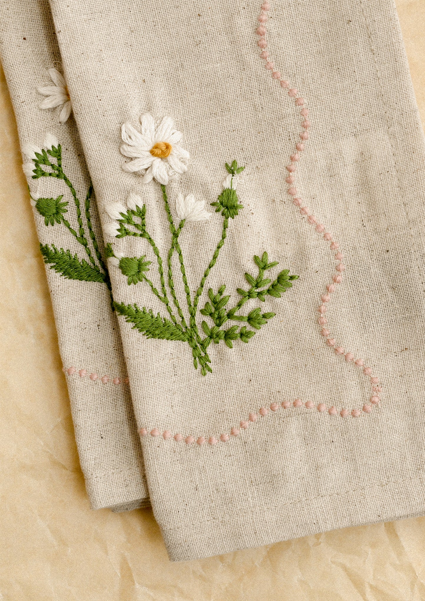 Embroidered floral design on a beige fabric background