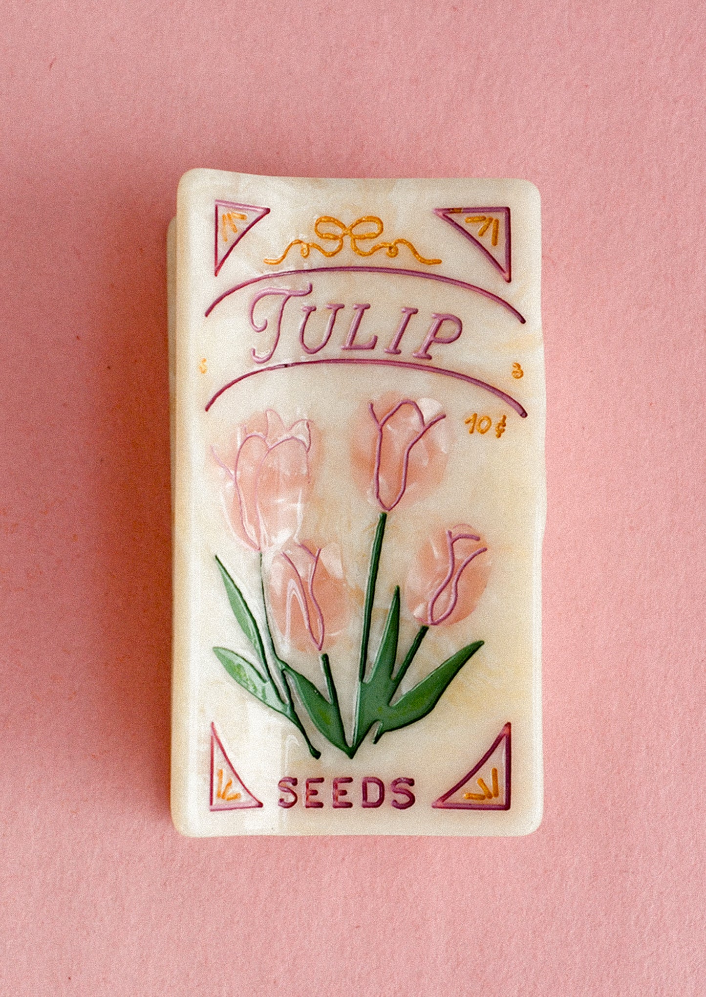 Vintage-style tulip seed packet style hair clip on a pink background