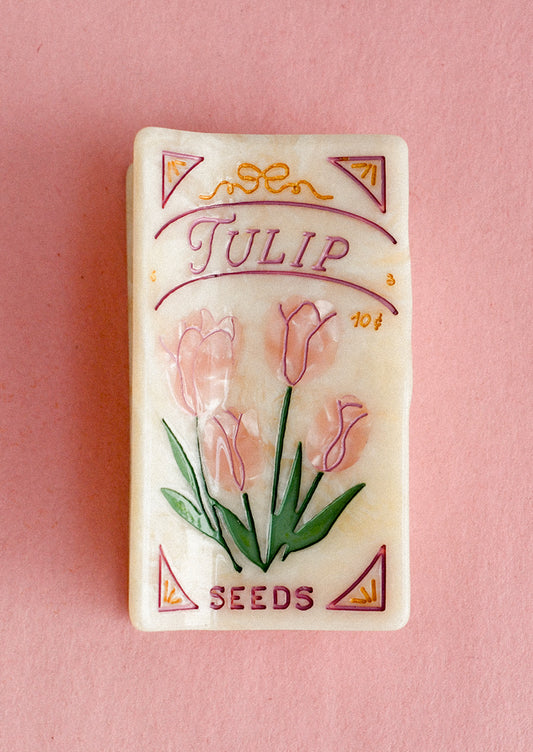 Vintage-style tulip seed packet style hair clip on a pink background