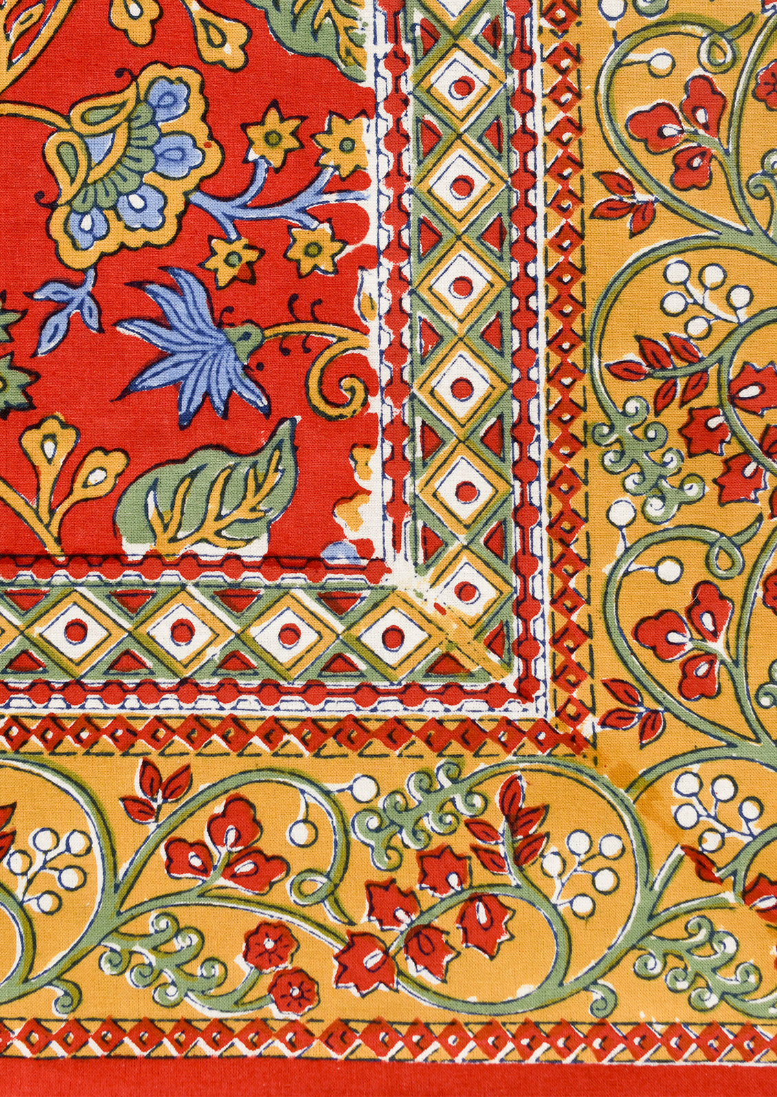 A block printed tablecloth in red with mustard, blue and green floral print.