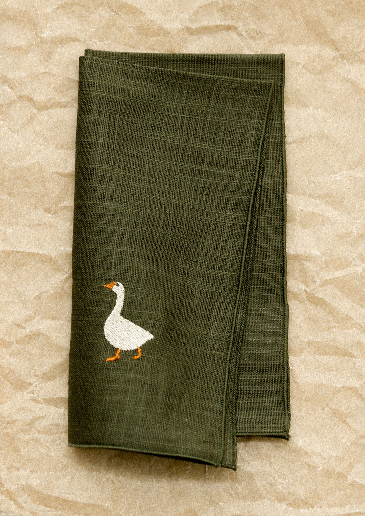 Green napkin with a goose design on a stone surface