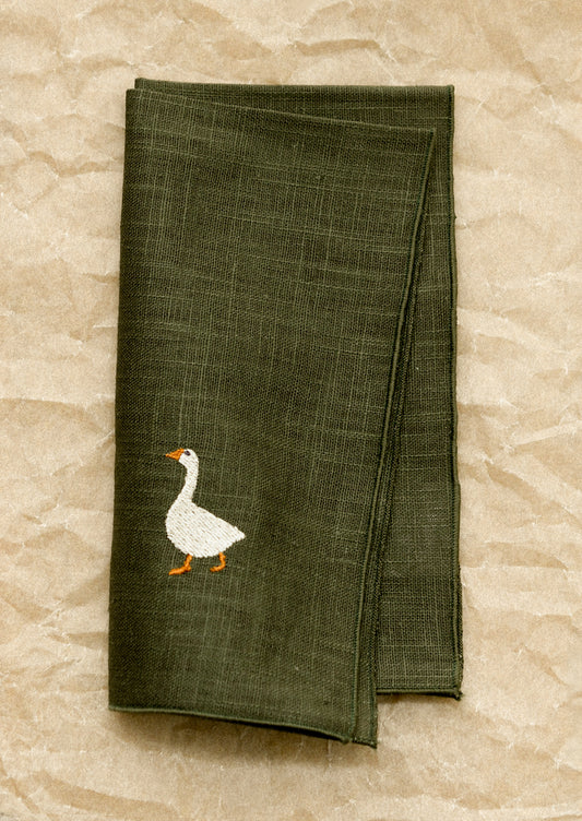 Green napkin with a goose design on a stone surface