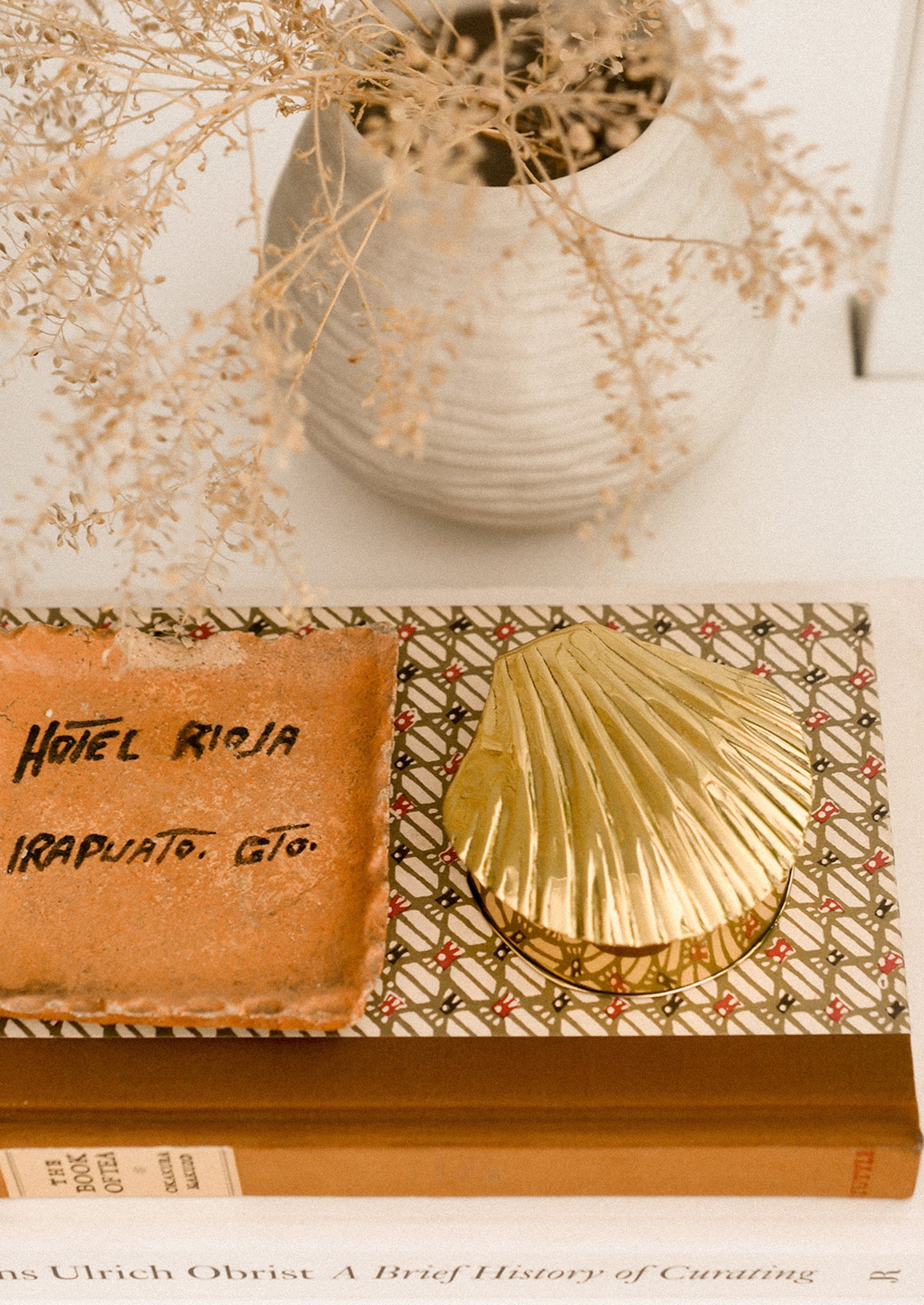 Decorative setting with a shell, book, and vase on a textured surface