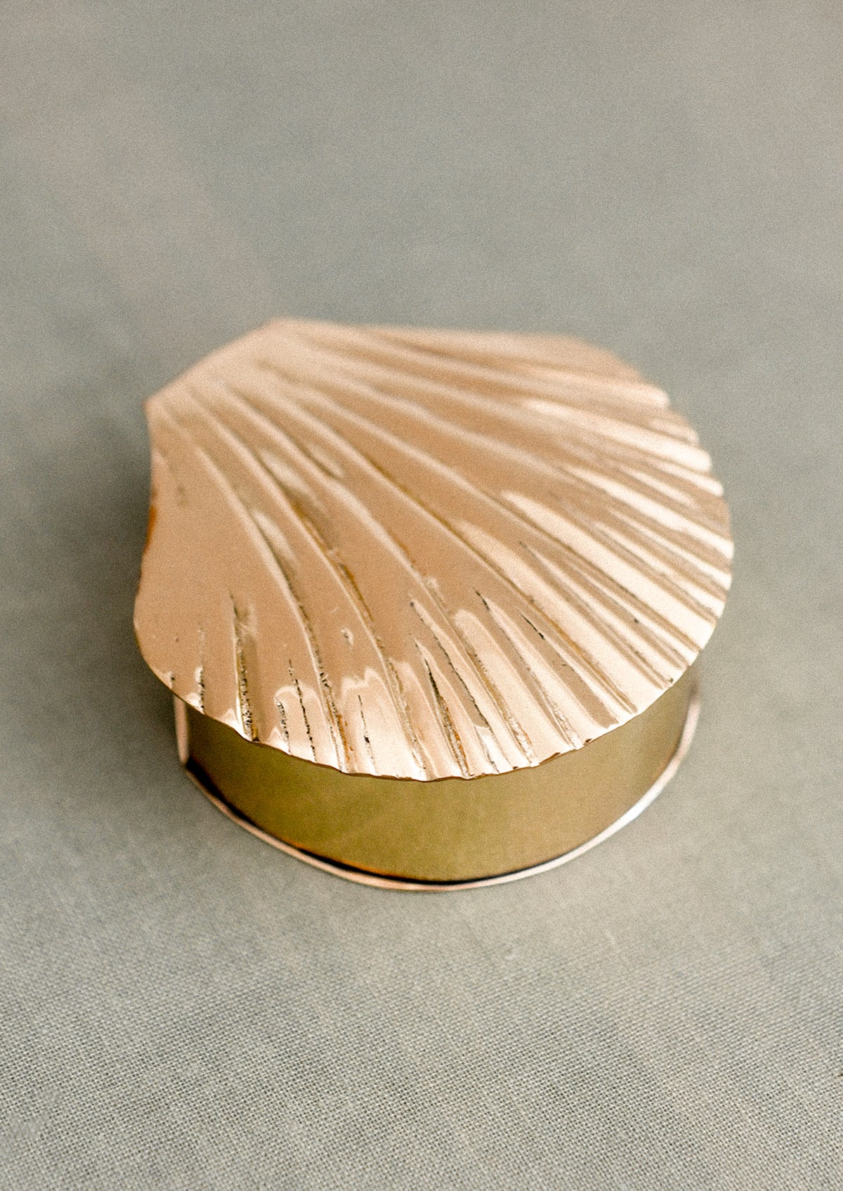 Gold shell-shaped jewelry box on a gray background