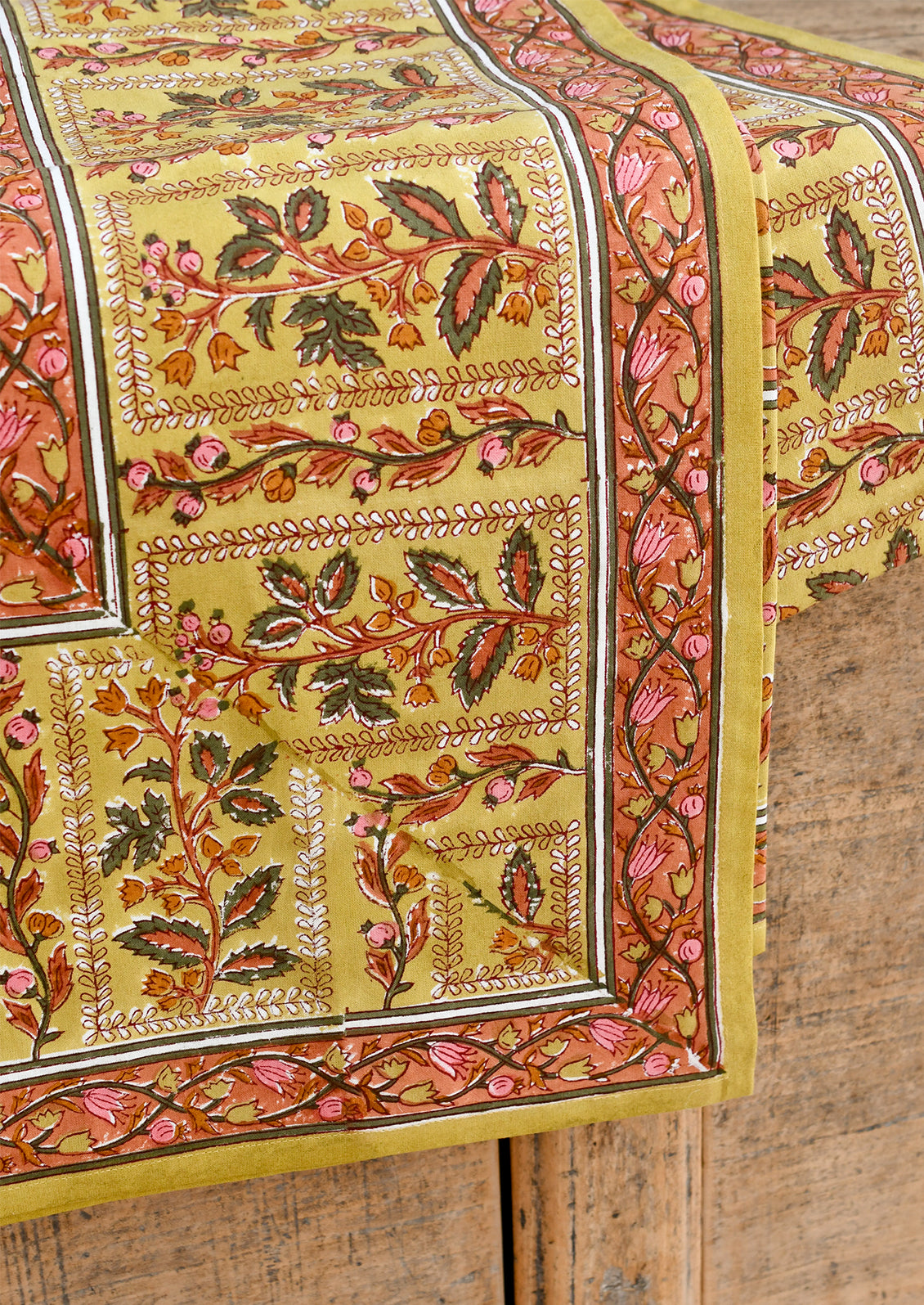 Decorative table cloth with intricate floral patterns on a wooden surface