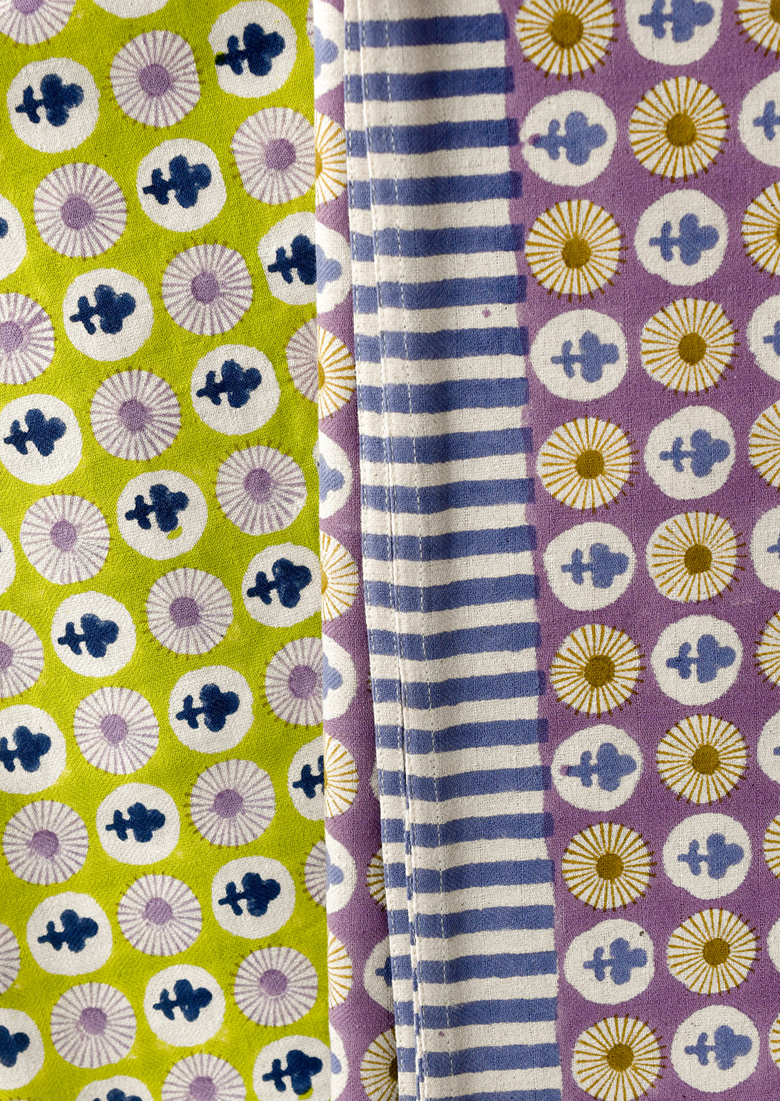 Fabric swatches with different patterns: green with white and blue floral, purple with white stripes, and purple with yellow floral.