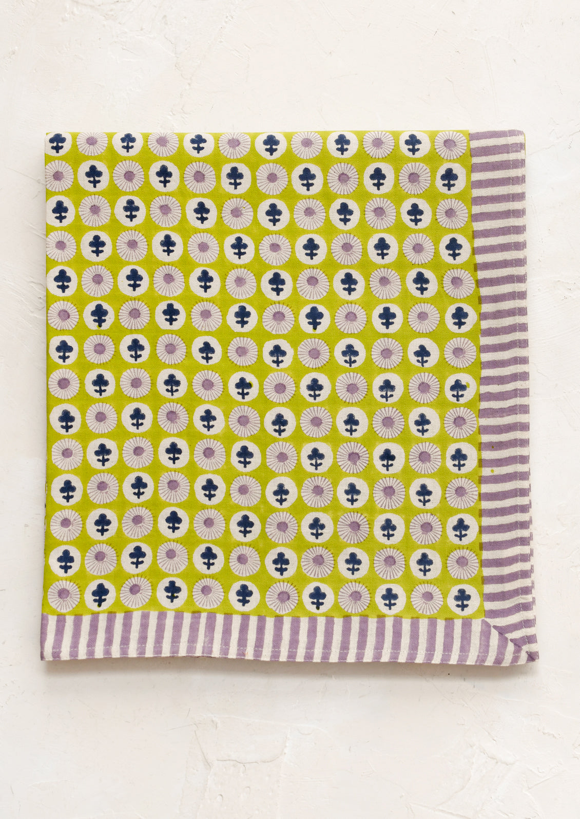 Patterned fabric with a green background and purple and white stripes on a white background