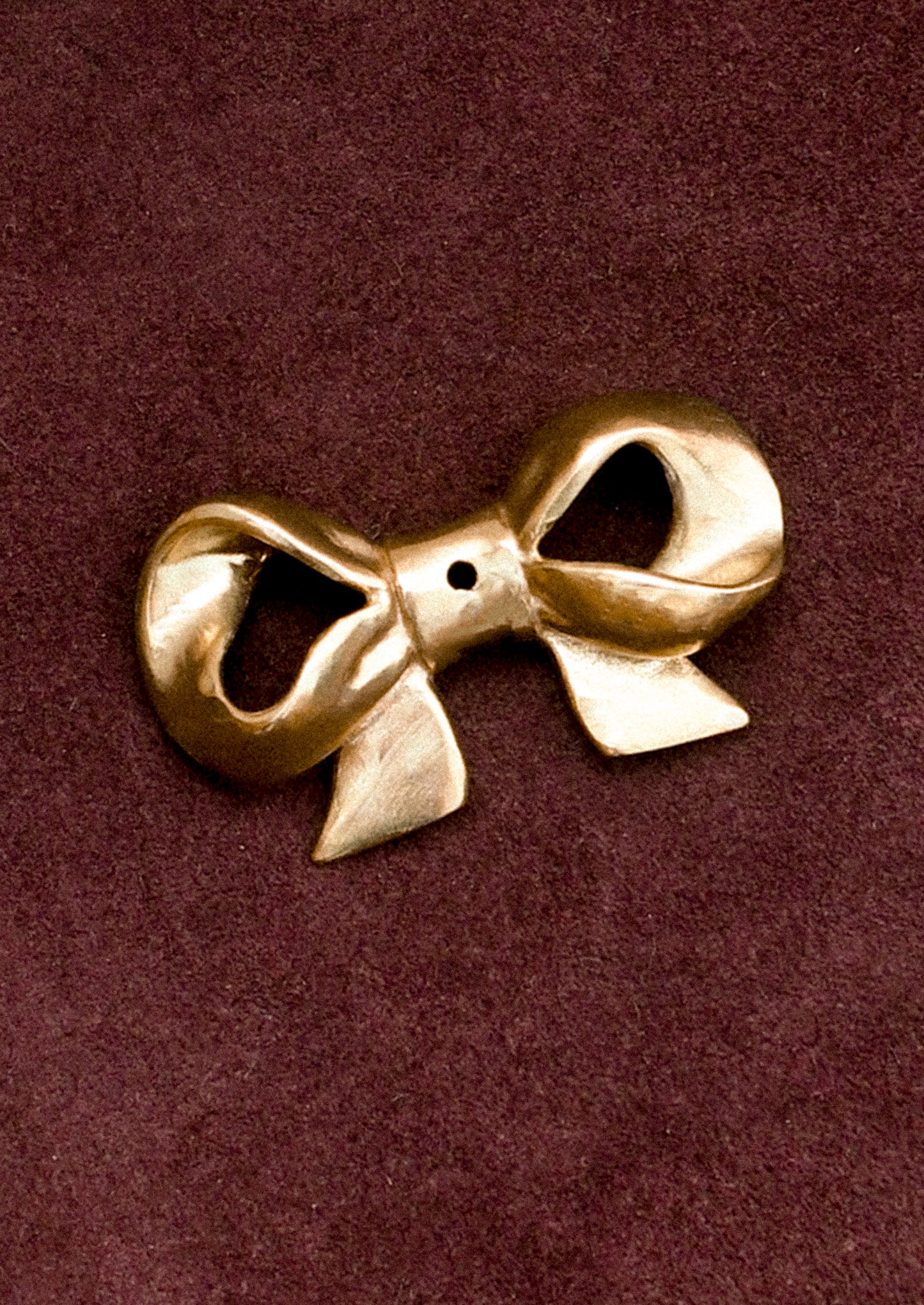 Brass bow-shaped incense holder on a brown background