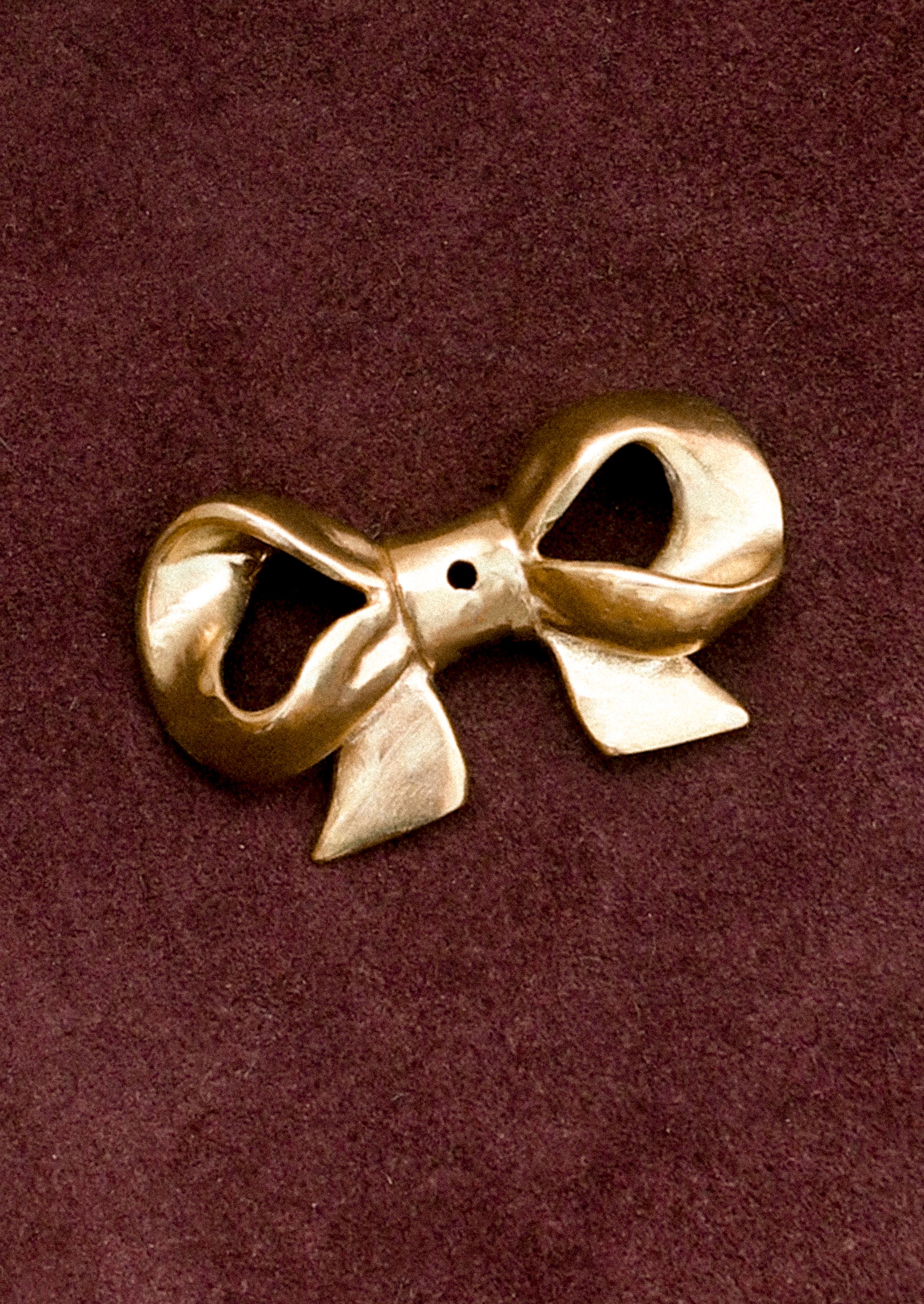 Brass bow-shaped incense holder on a brown background