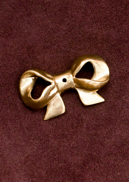 Brass bow-shaped incense holder on a brown background