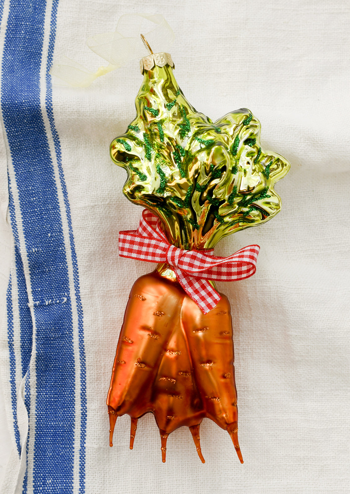 A glass ornament depicting a bundle of carrots tied with red gingham ribbon.