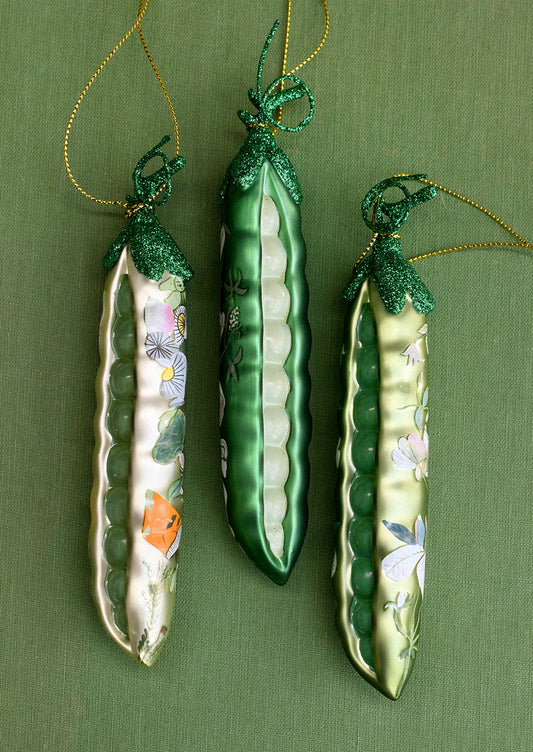 Glass ornaments depicting peapods with floral patterns on them.
