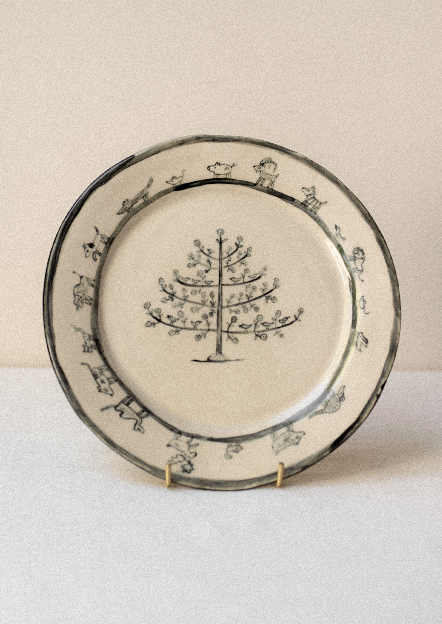 A cream plate with animal and tree drawing in dark grey.