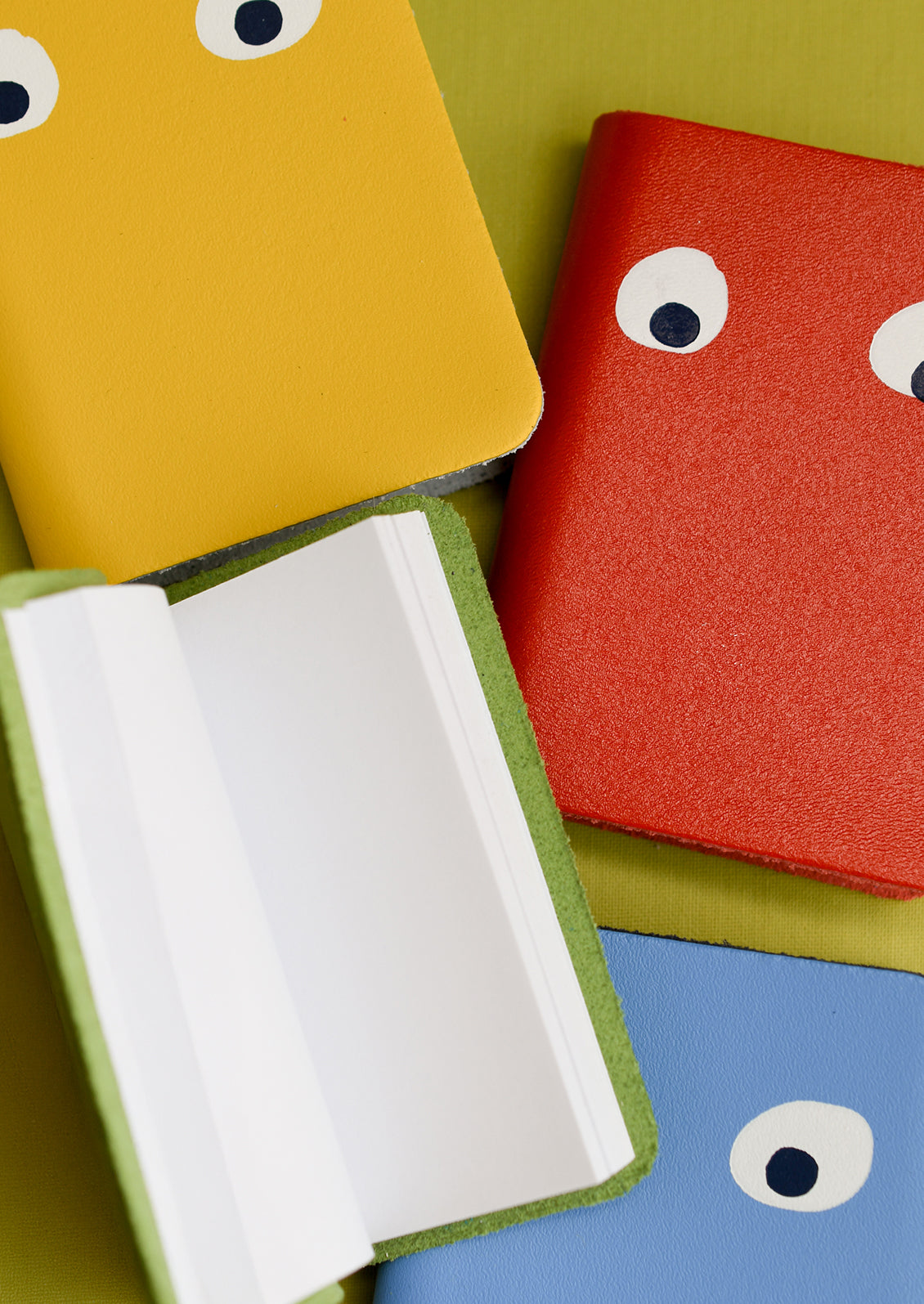 Four leather notebooks with pair of eyes painted on cover.