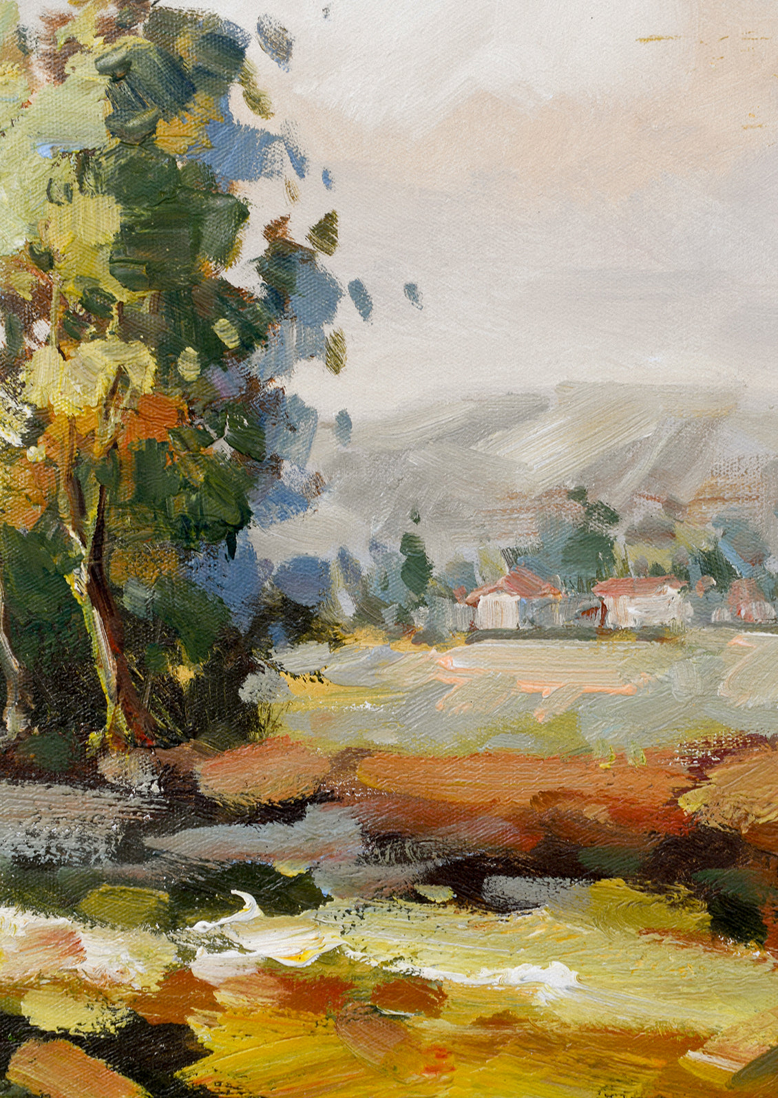 A framed original landscape oil painting of the countryside with houses in the distance.