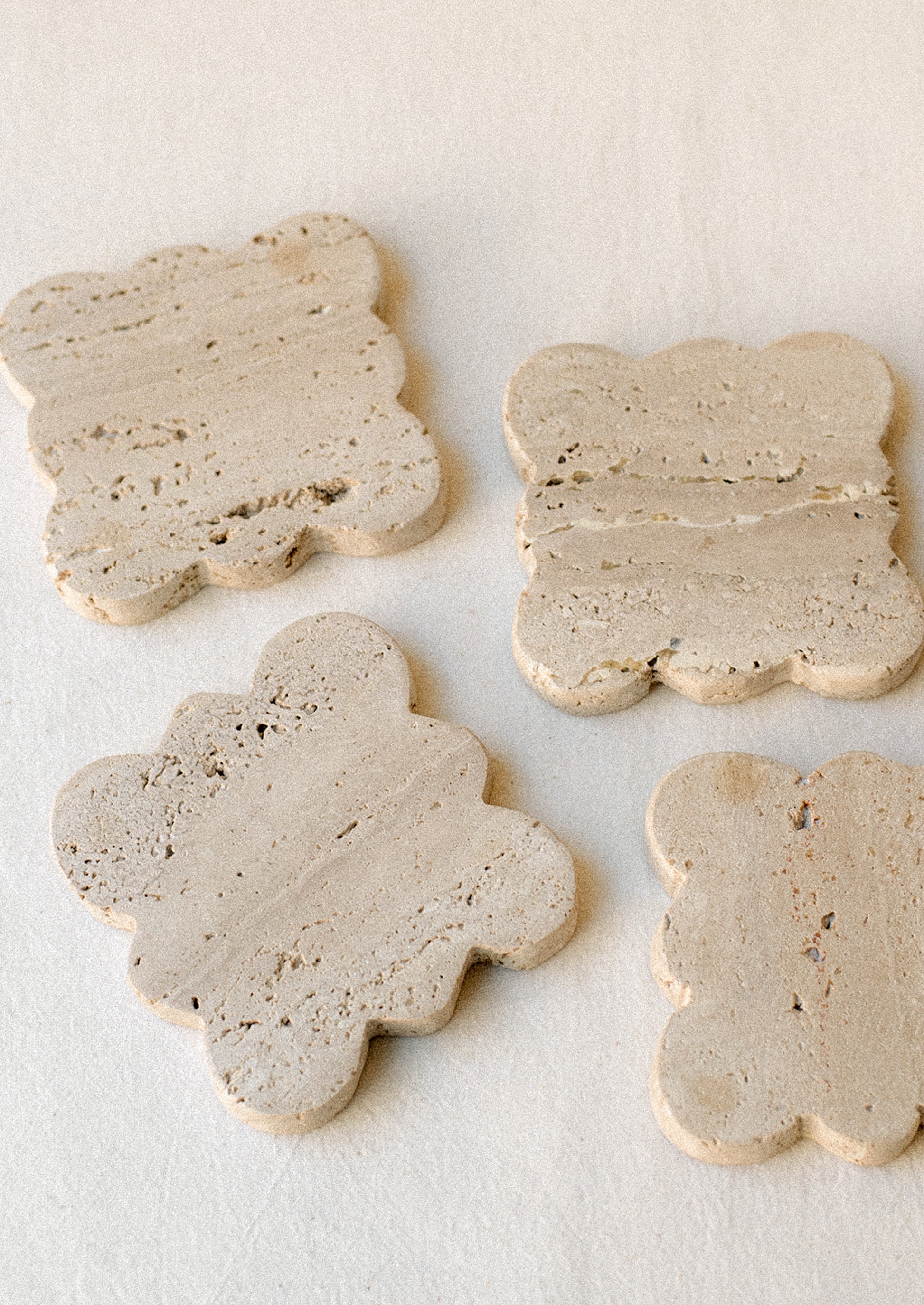A set of square travertine coasters with scalloped edges.