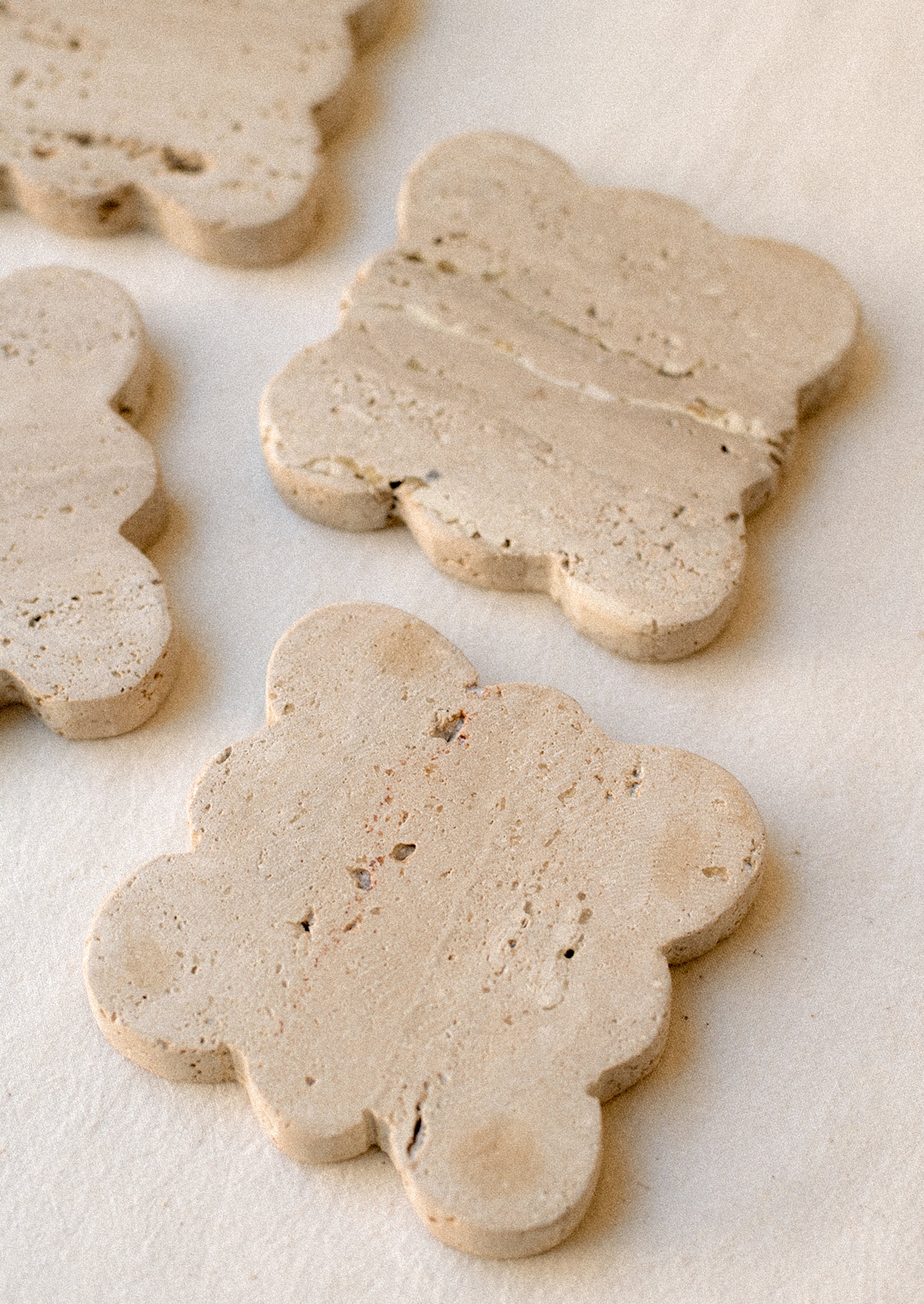 A set of square travertine coasters with scalloped edges.