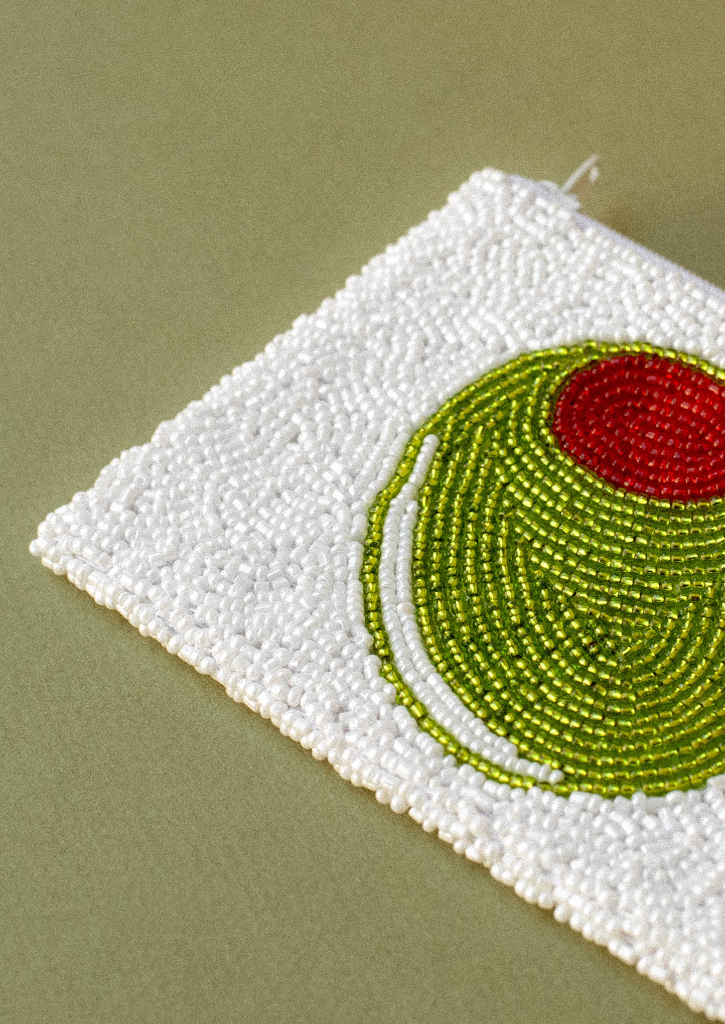A white beaded coin pouch with green pimento olive design.