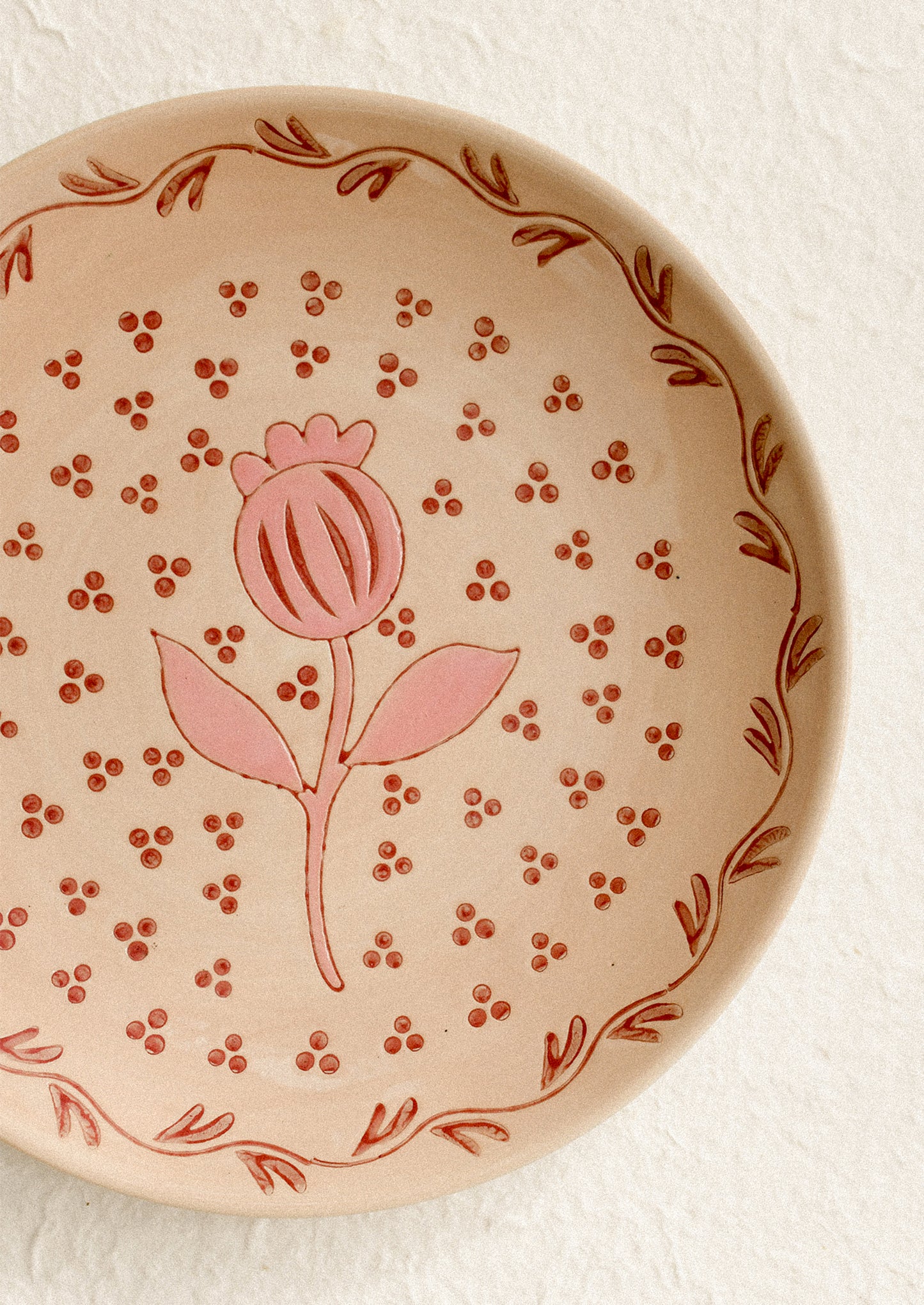 A round plate in sand color with pink floral print.