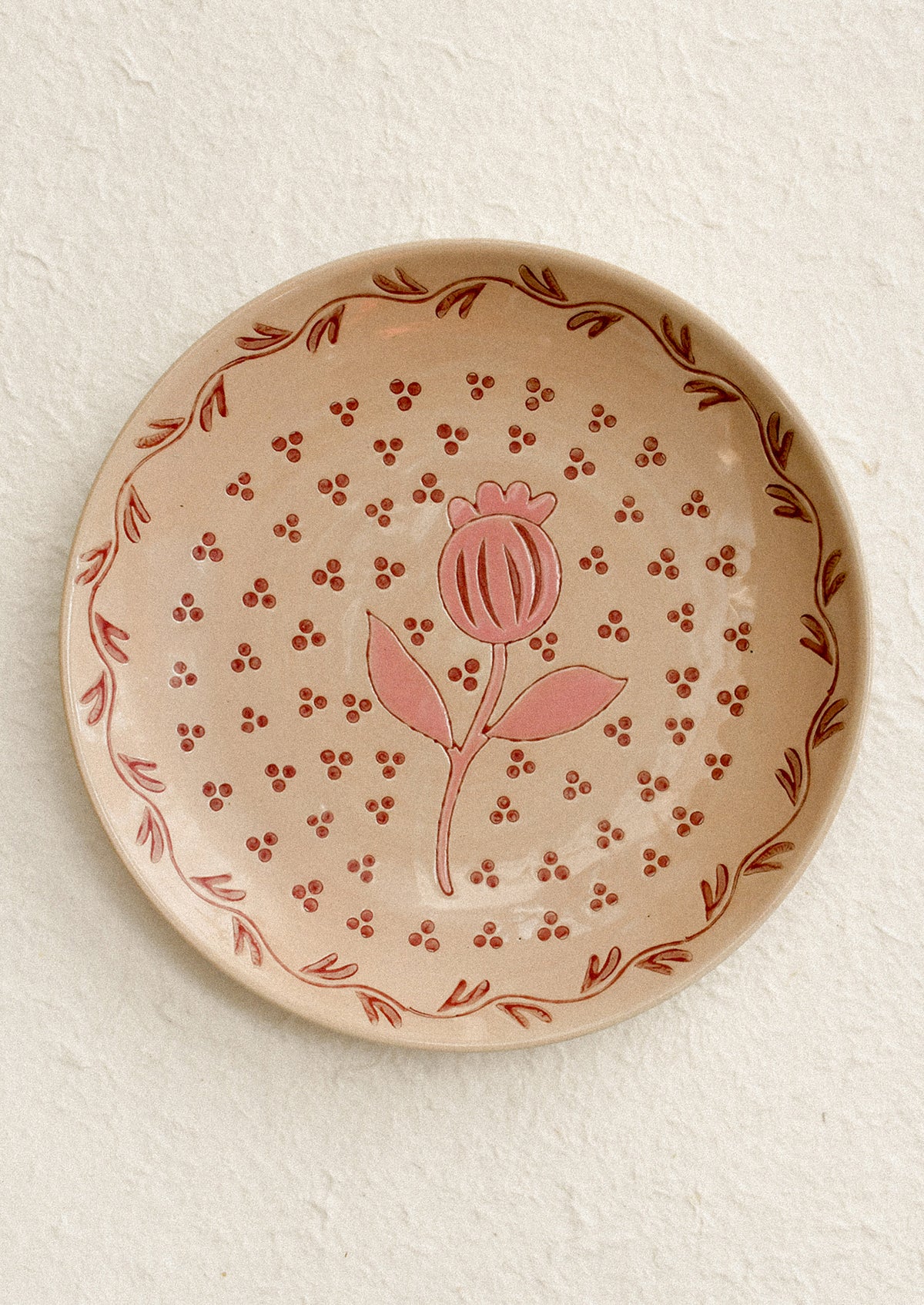 A round plate in sand color with pink floral print.