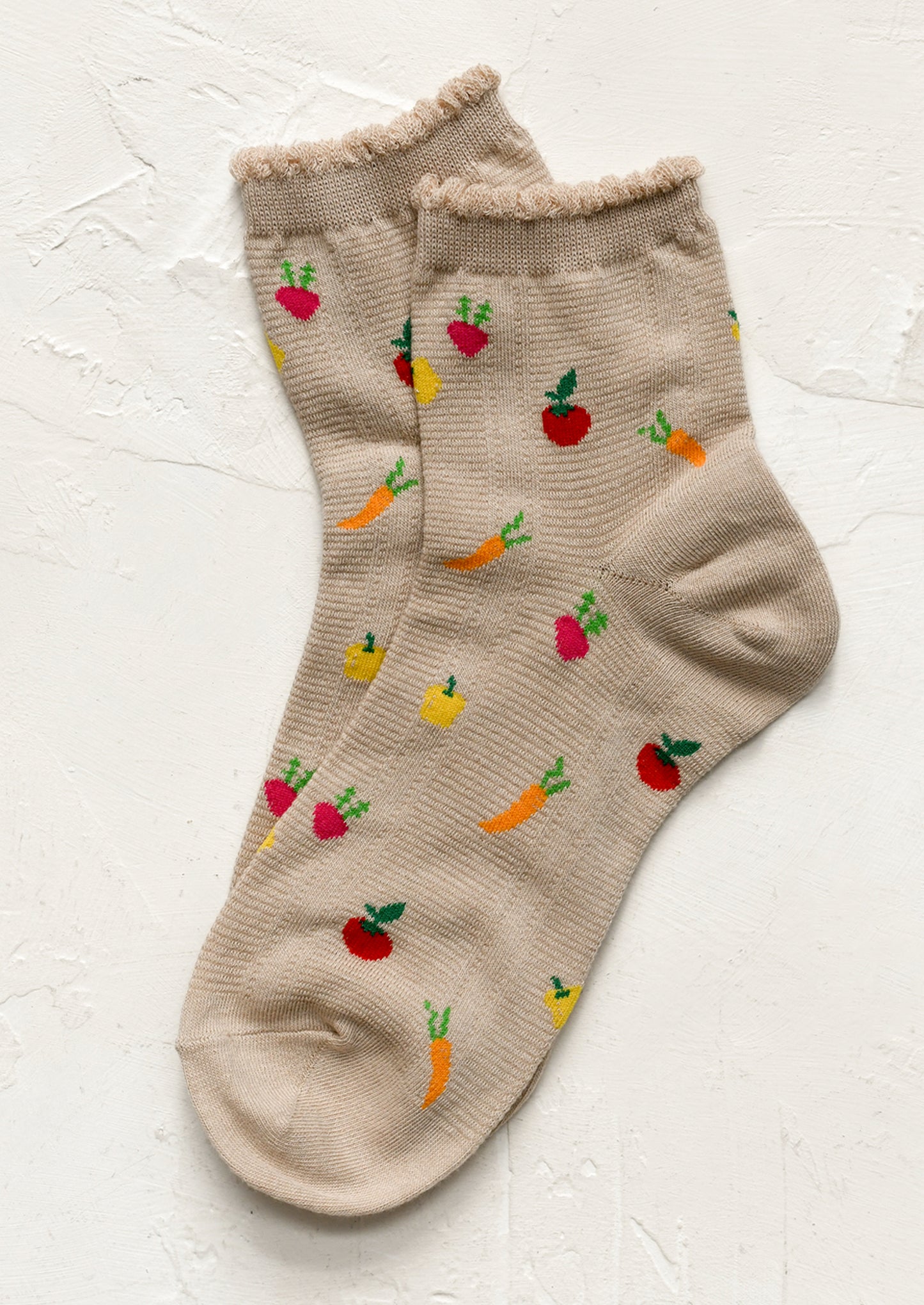 A pair of beige socks with all over vegetable motif.