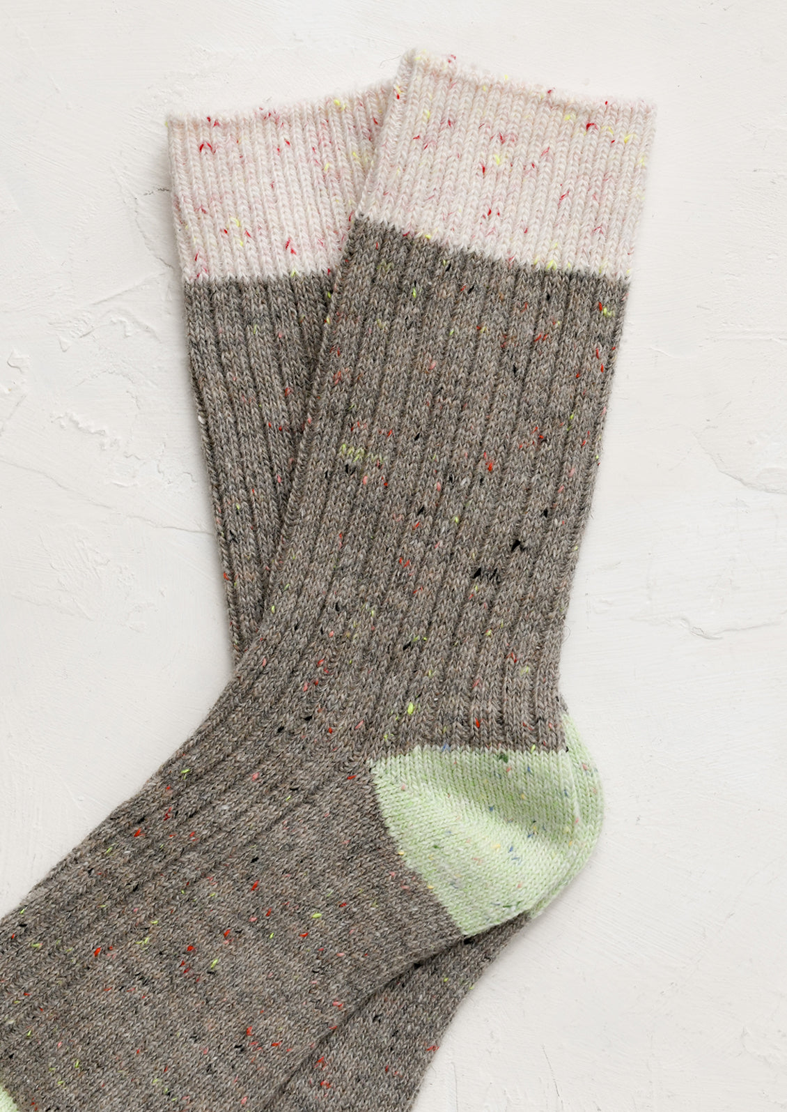 A pair of taupe socks with pink and green contrast.
