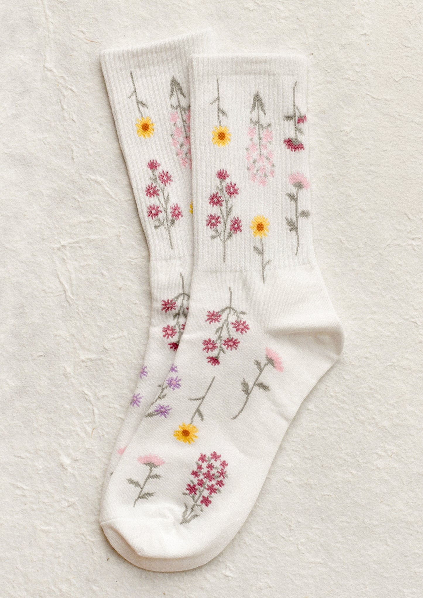 A pair of white socks with pink and yellow flower pattern.