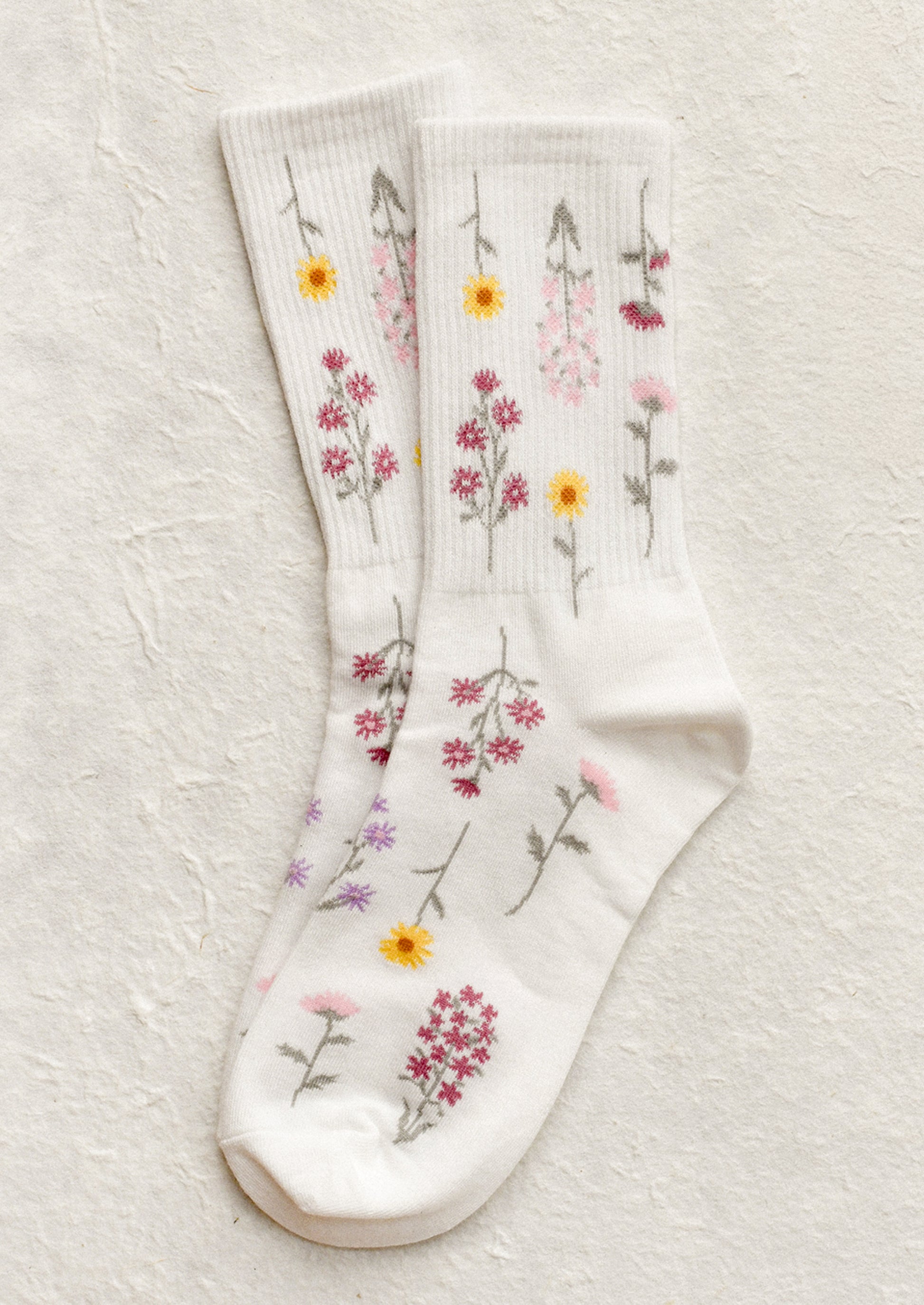 A pair of white socks with pink and yellow flower pattern.