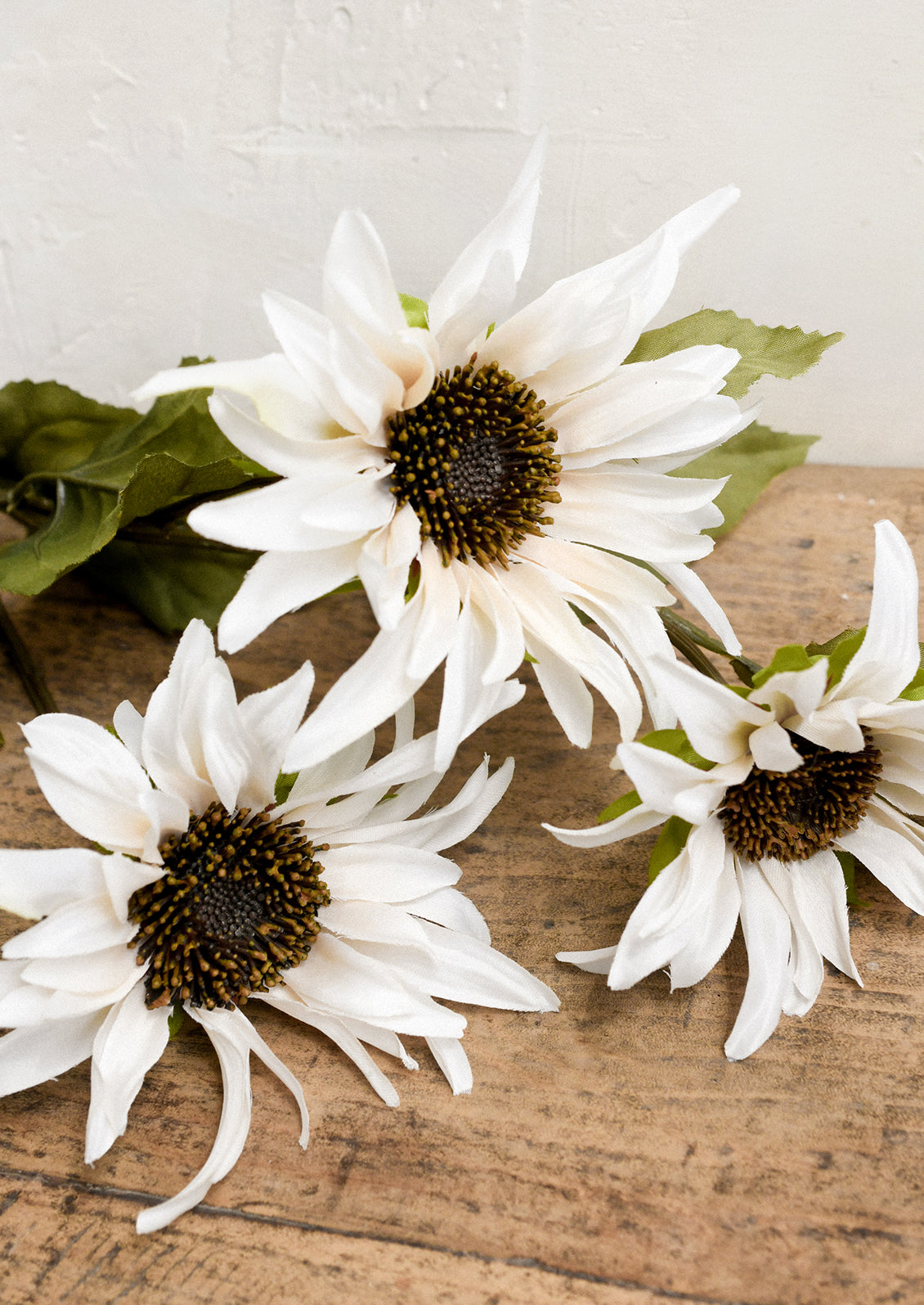 A faux floral spray depicting cream colored sunflowers.