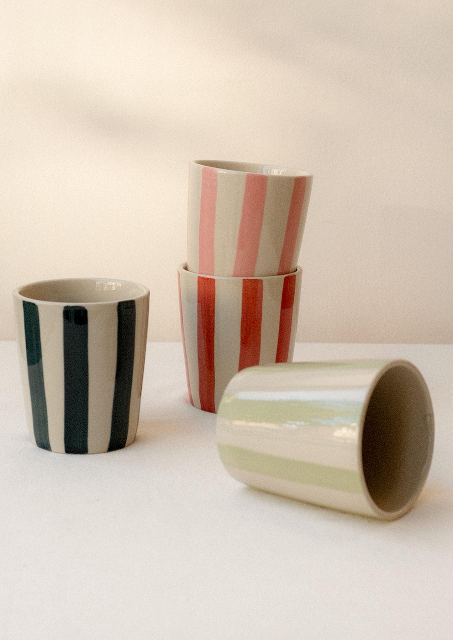A stack of striped ceramic tumblers in assorted colors.
