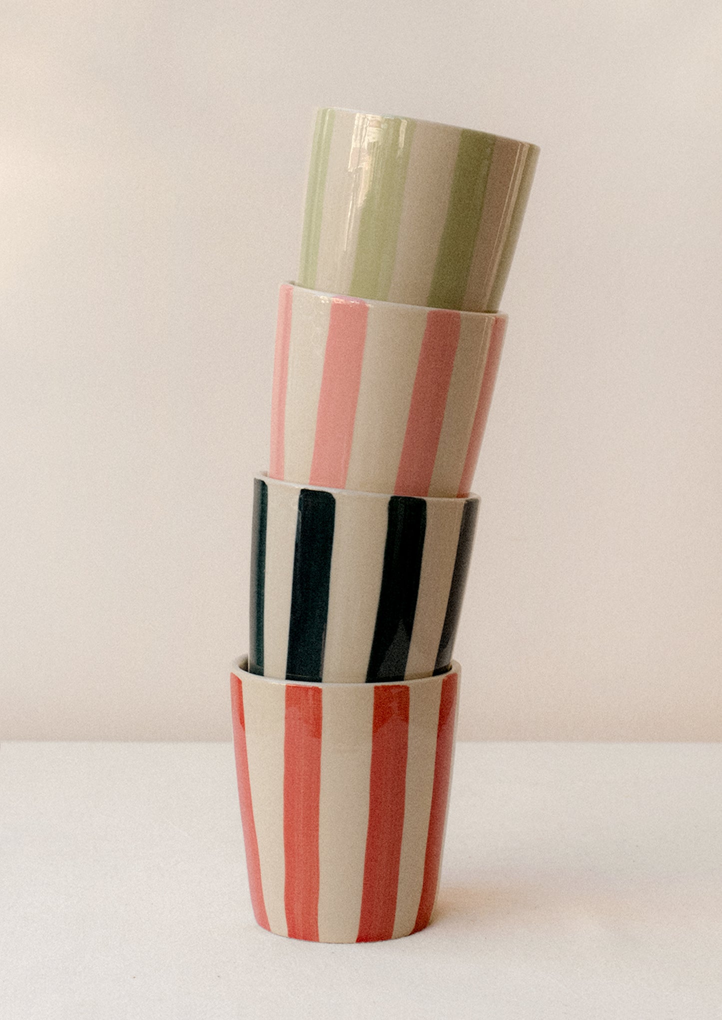 A stack of striped ceramic tumblers in assorted colors.