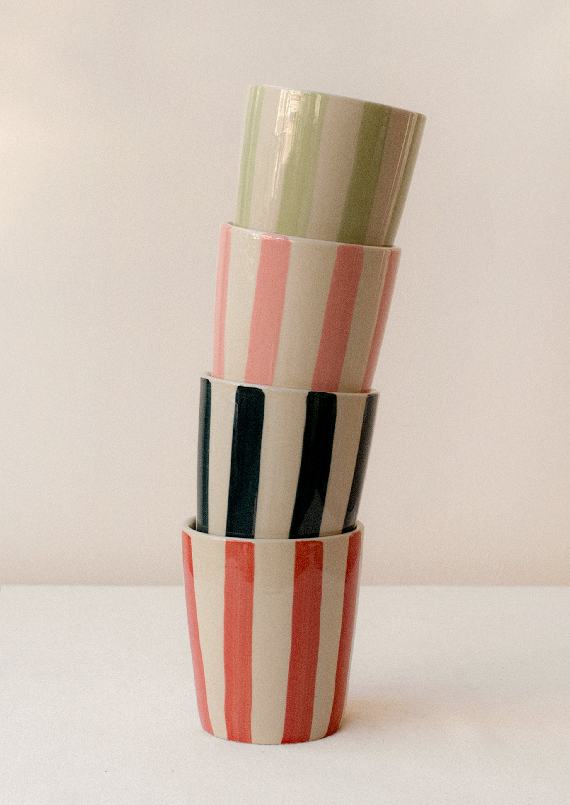 A stack of striped ceramic tumblers in assorted colors.