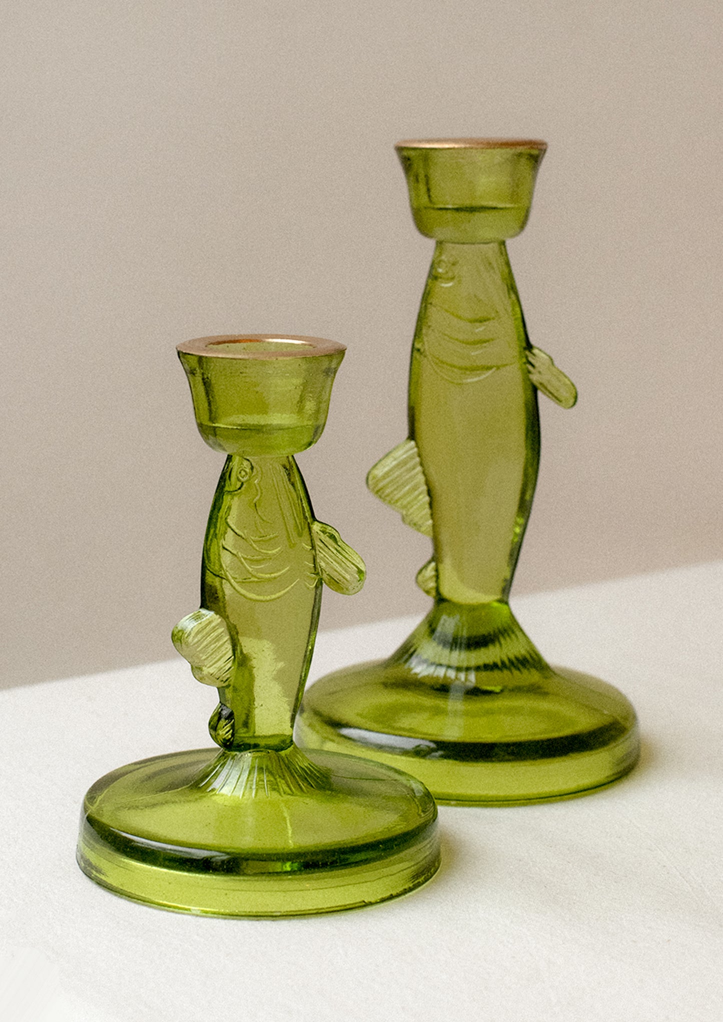 A green tinted translucent glass candle holder in the shape of a fish.