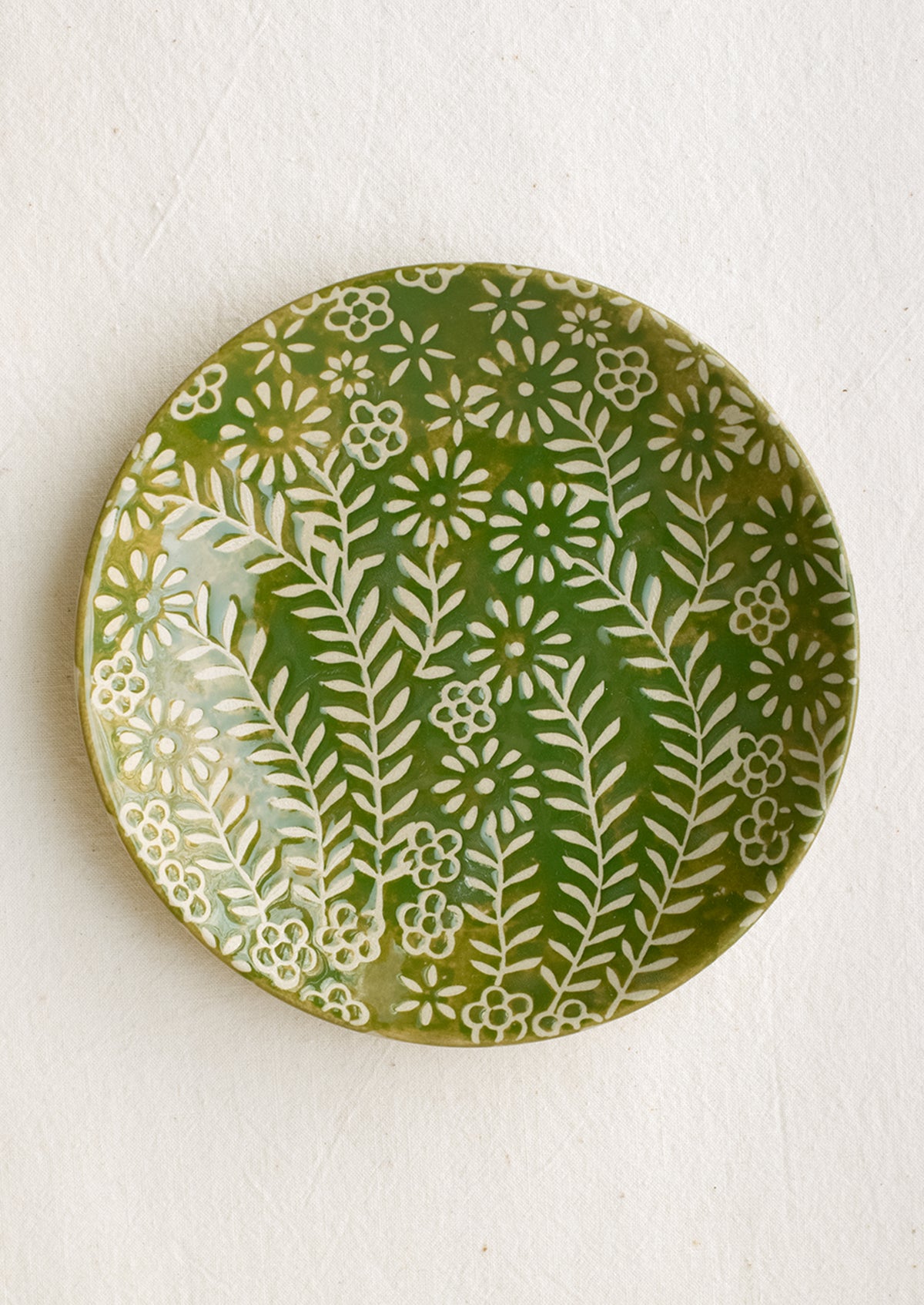 A small side plate with wax relief floral pattern in green and ivory.