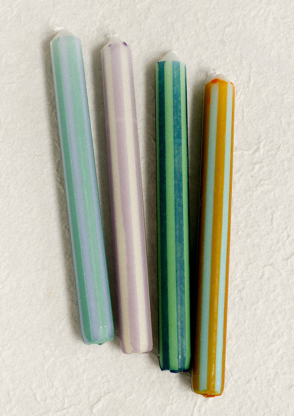 Pinstripe print taper candles in four color options.