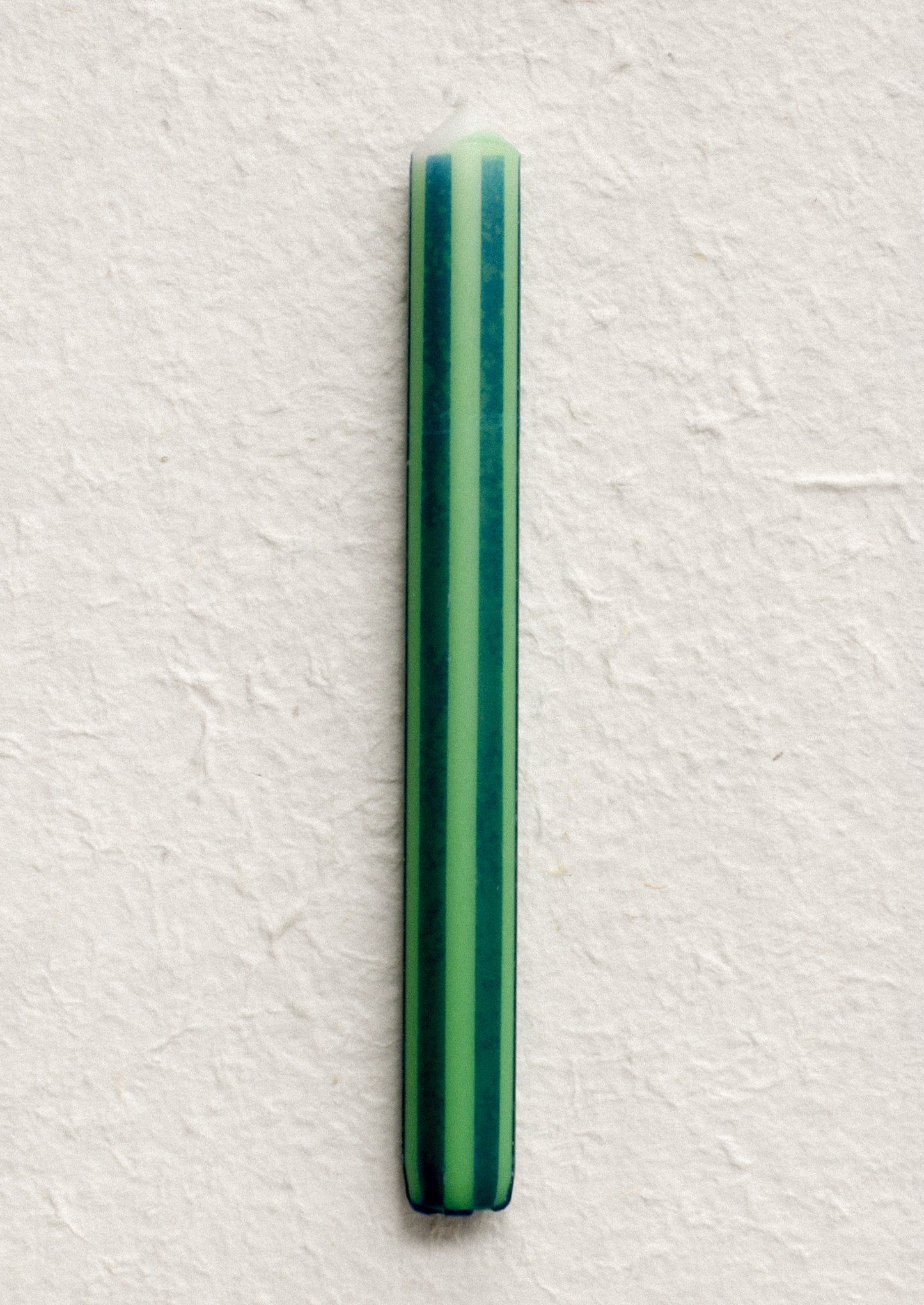 A pinstripe patterned candle in green and teal stripes.