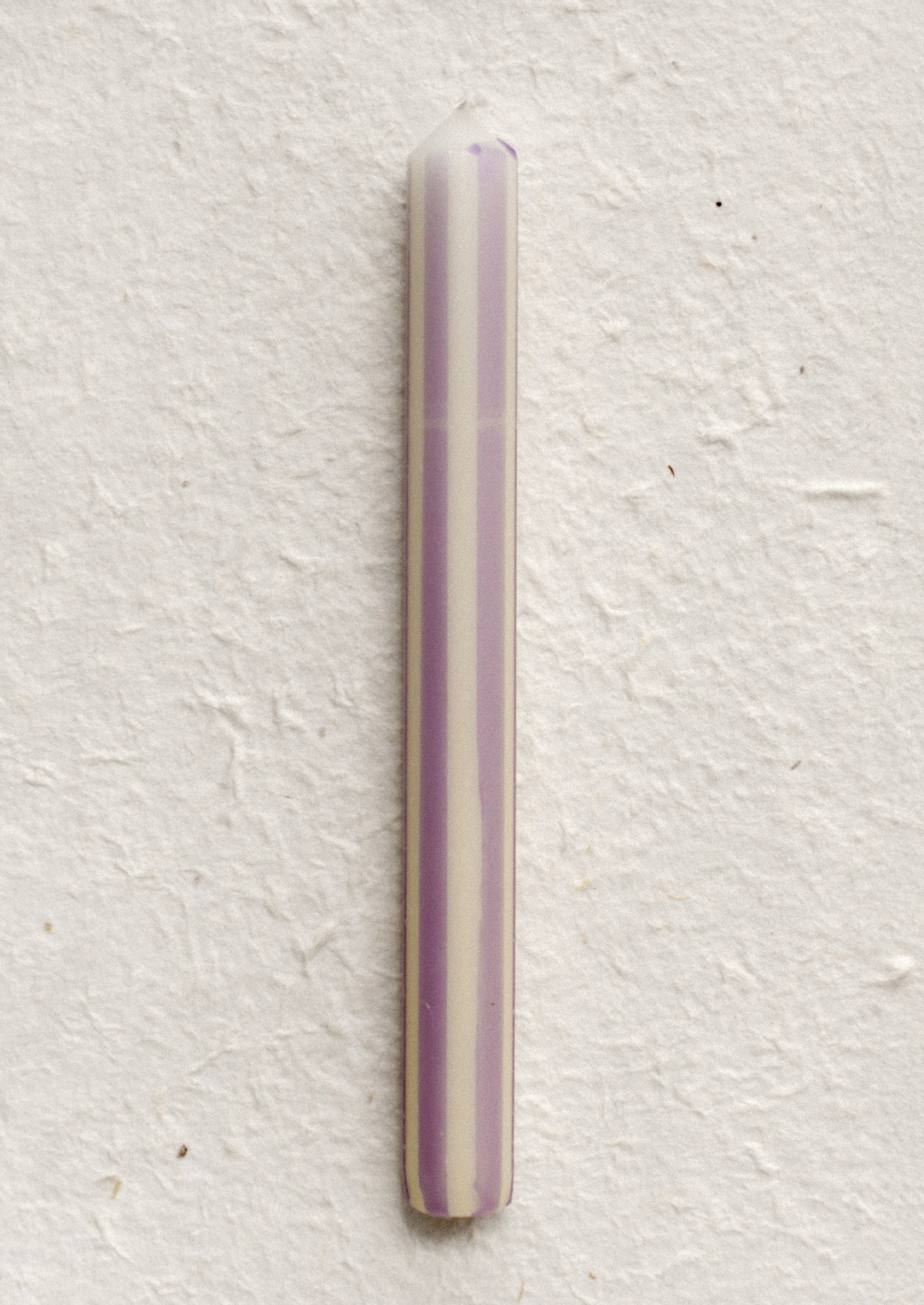 A pinstripe patterned candle in ivory and lavender stripes.