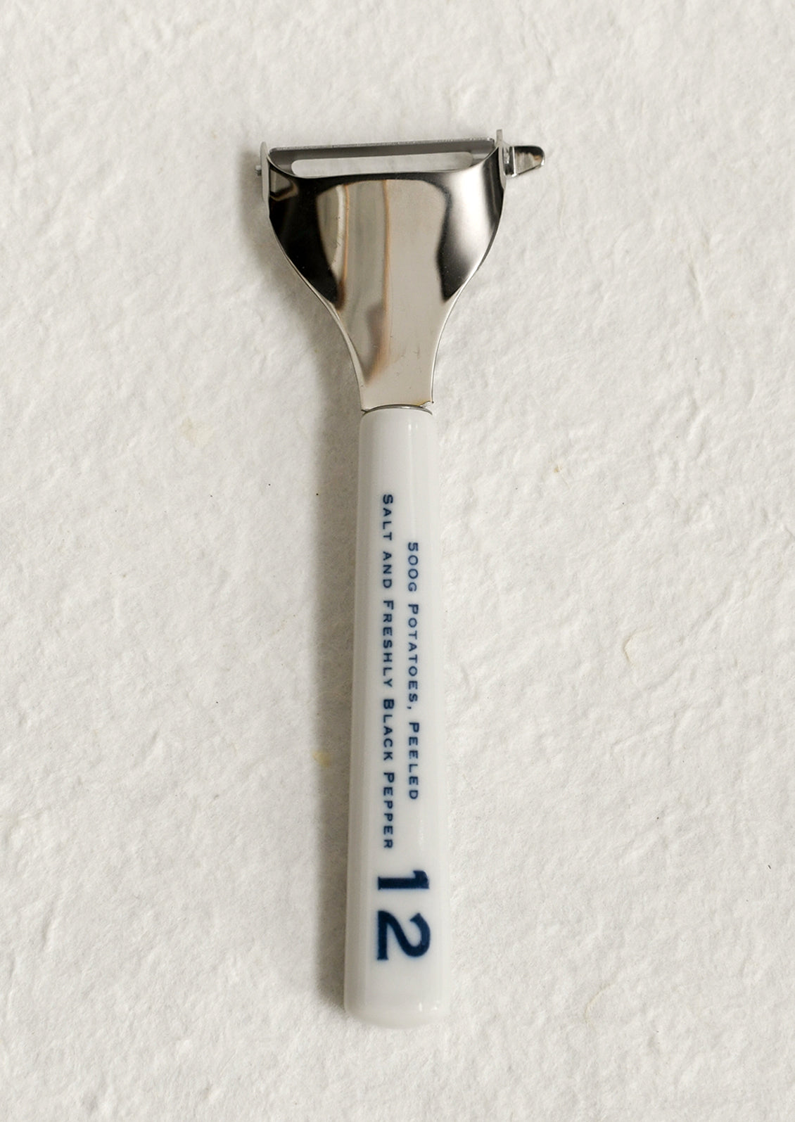 A vegetable peeler with ceramic white and blue handle with blue text.