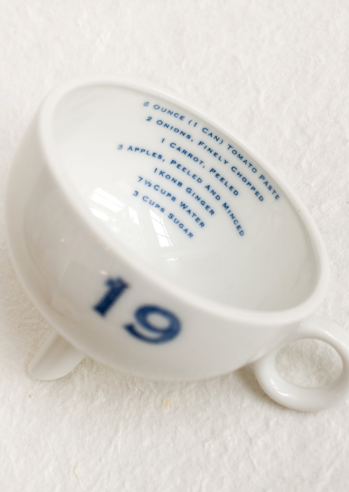 A ceramic funnel in white with printed blue text.