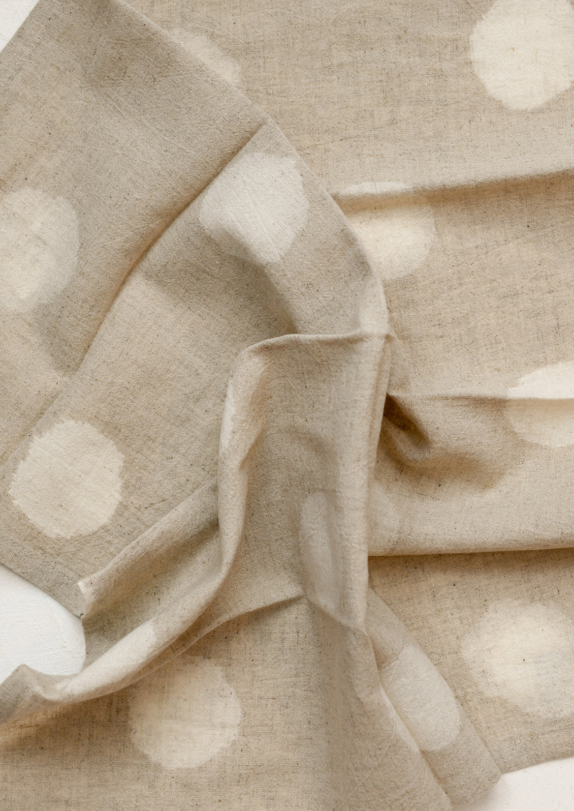 A pair of natural colored napkins with polka dot resist pattern.