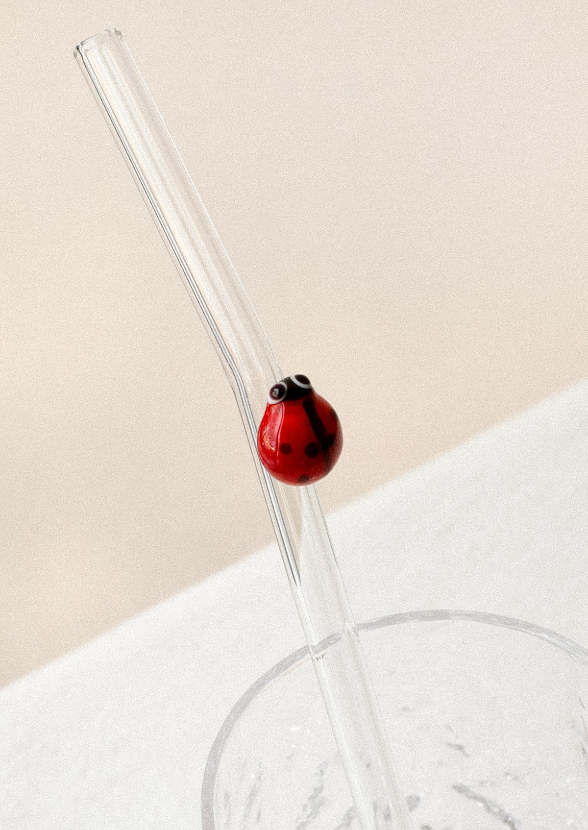 A clear glass straws with bent shape, with lampwork ladybug figurine.