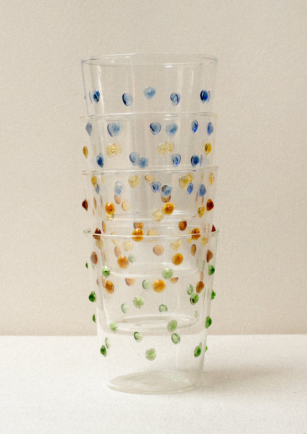 Four clear glass tumblers with textured raised dots on outside, in four color options.