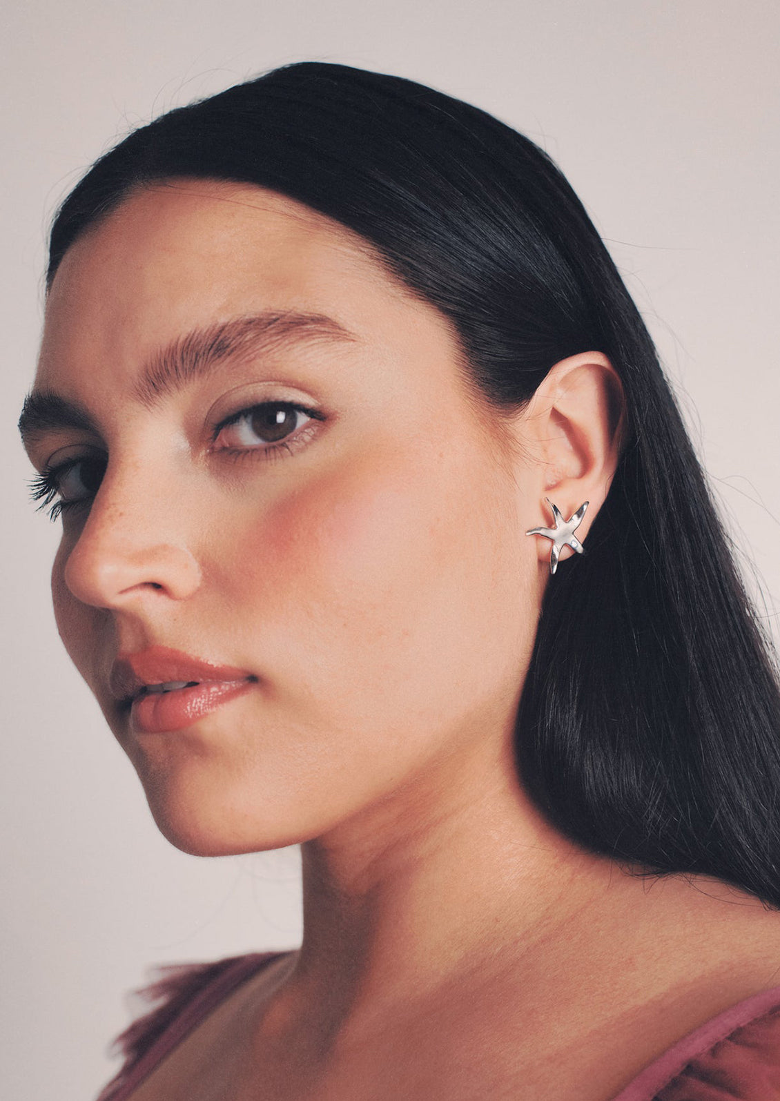 A woman wearing a pair of silver star earrings.
