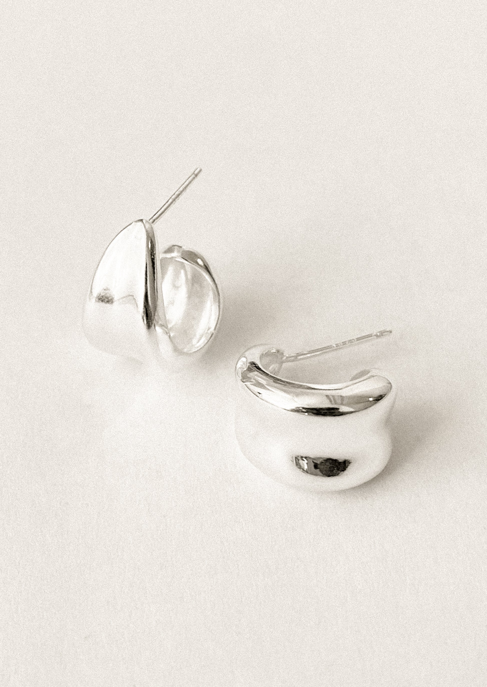 A pair of sterling silver hoop earrings with curled side detail.