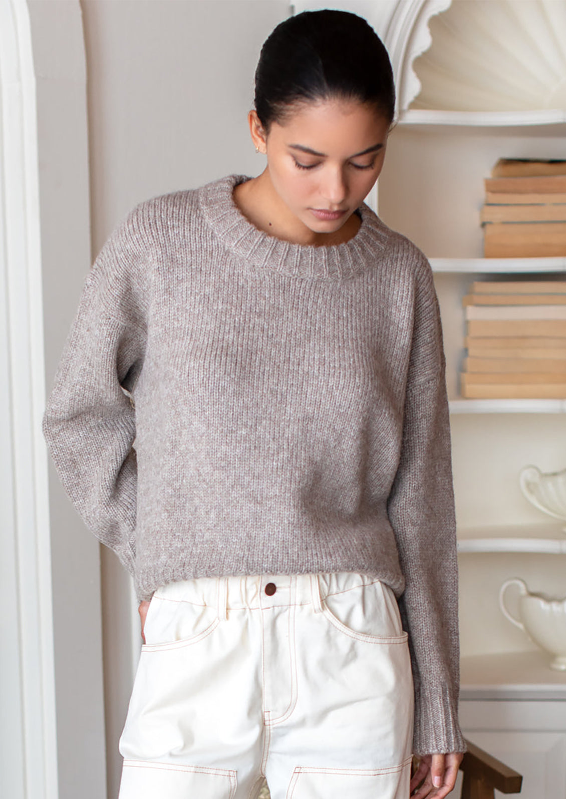 A woman wearing a round neck sweater with ribbed hem and cuffs.